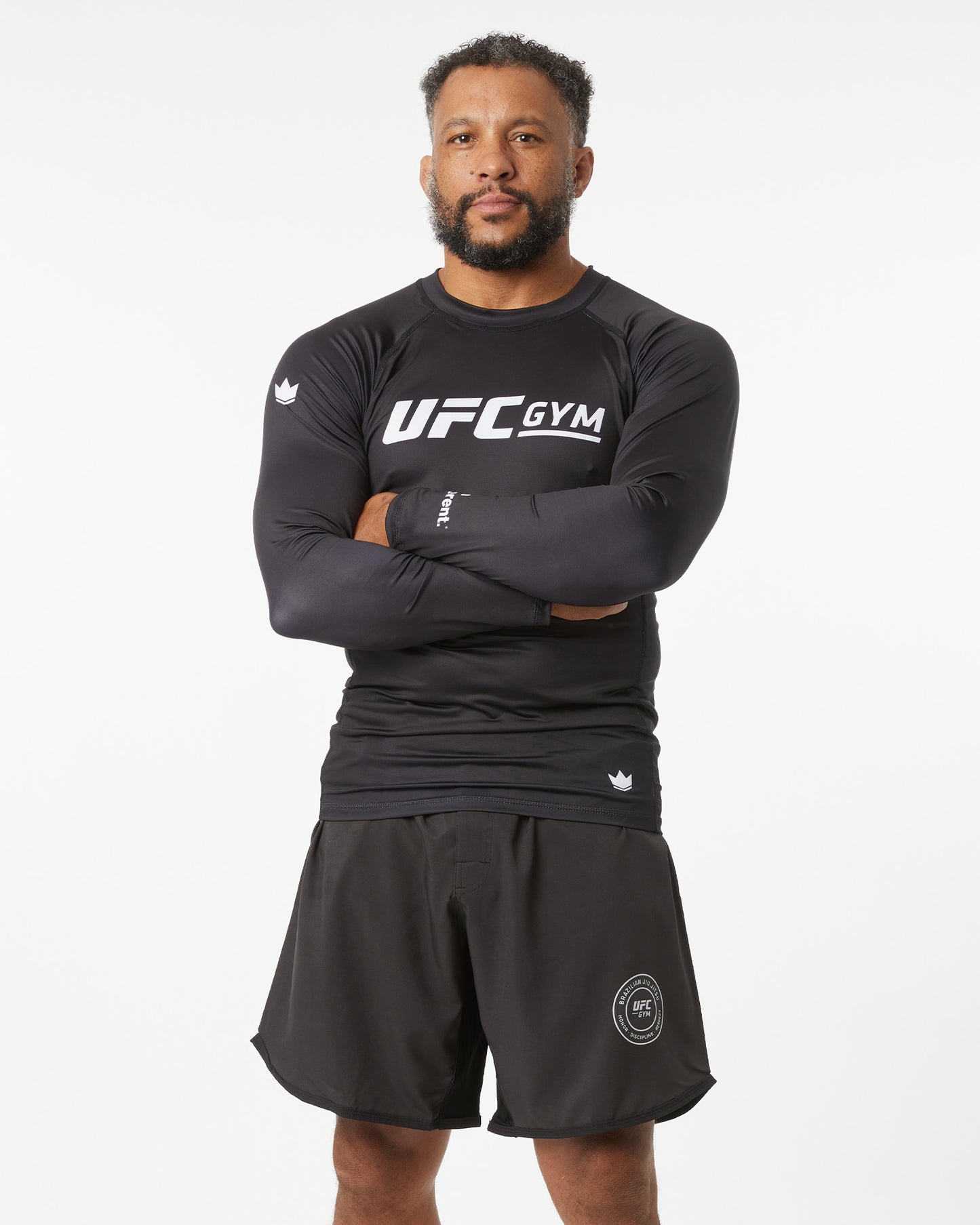 Man wearing a black UFC Gym outfit on a white background with his arms crossed