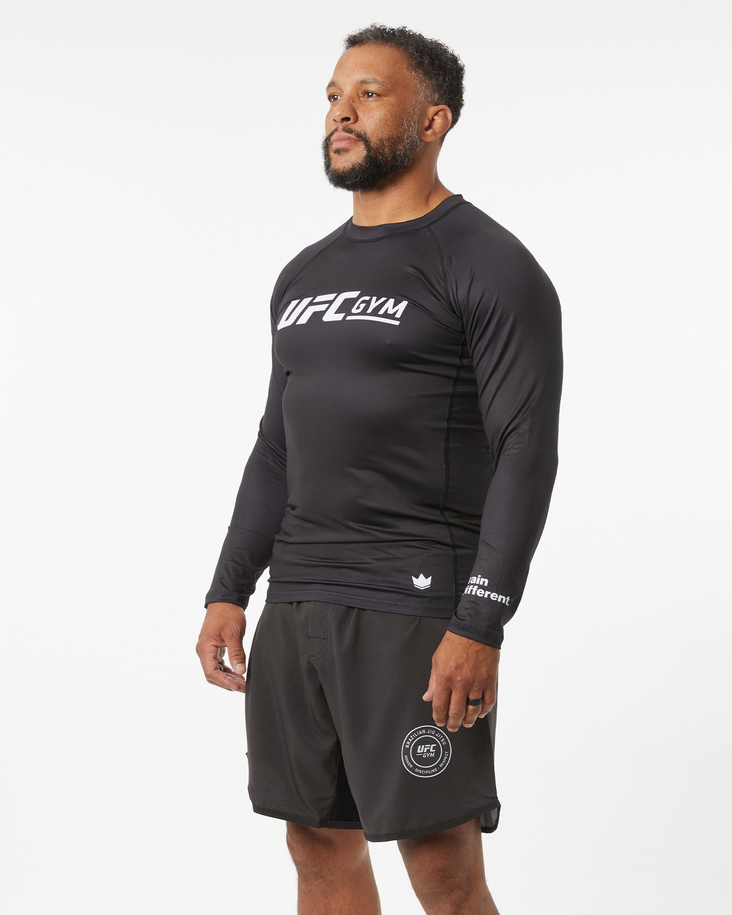 Person wearing a black UFC Gym long-sleeve shirt and shorts on a white background in a right-facing angle