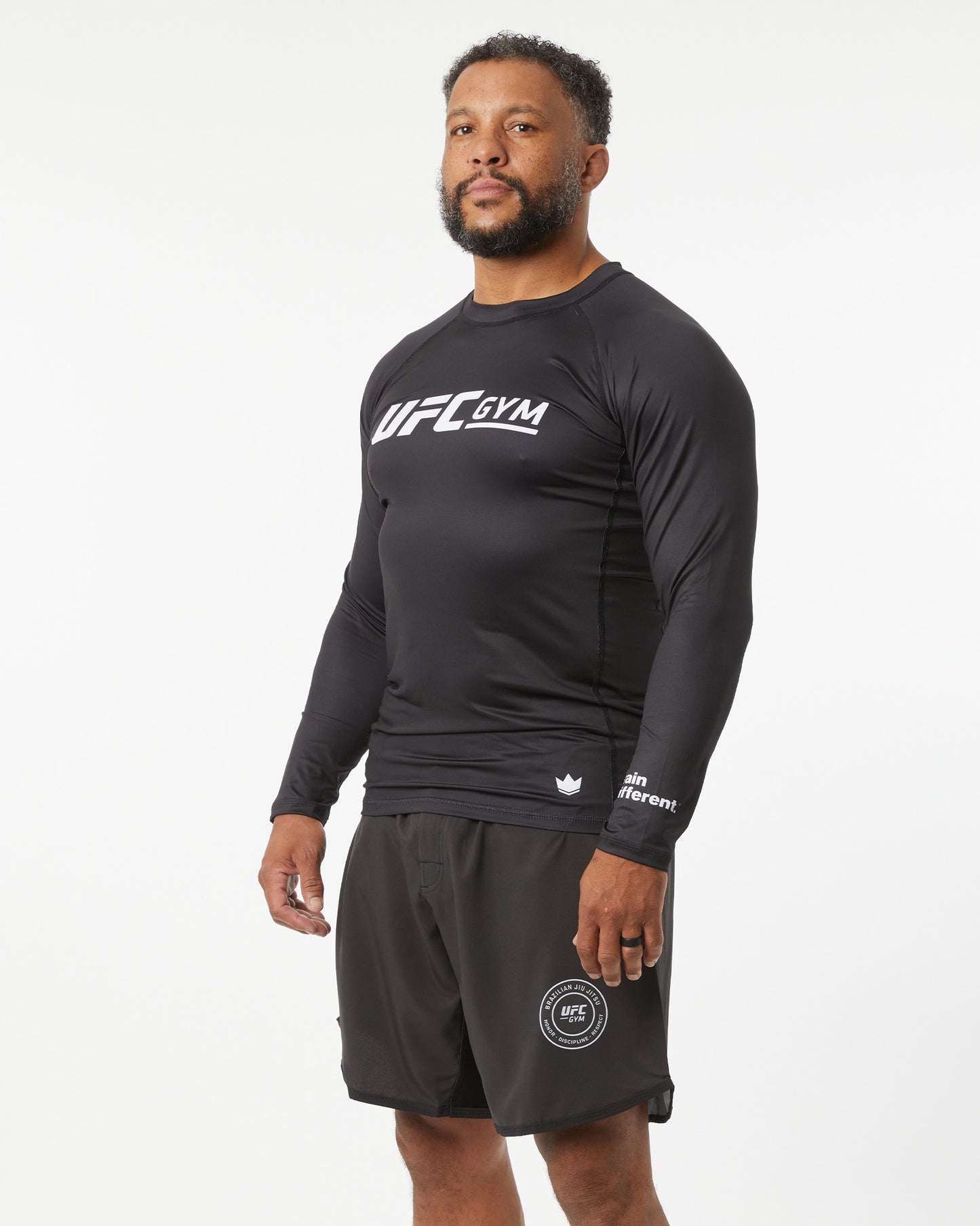 Person wearing a black UFC Gym long-sleeve shirt and shorts on a white background facing in a slight-right angle