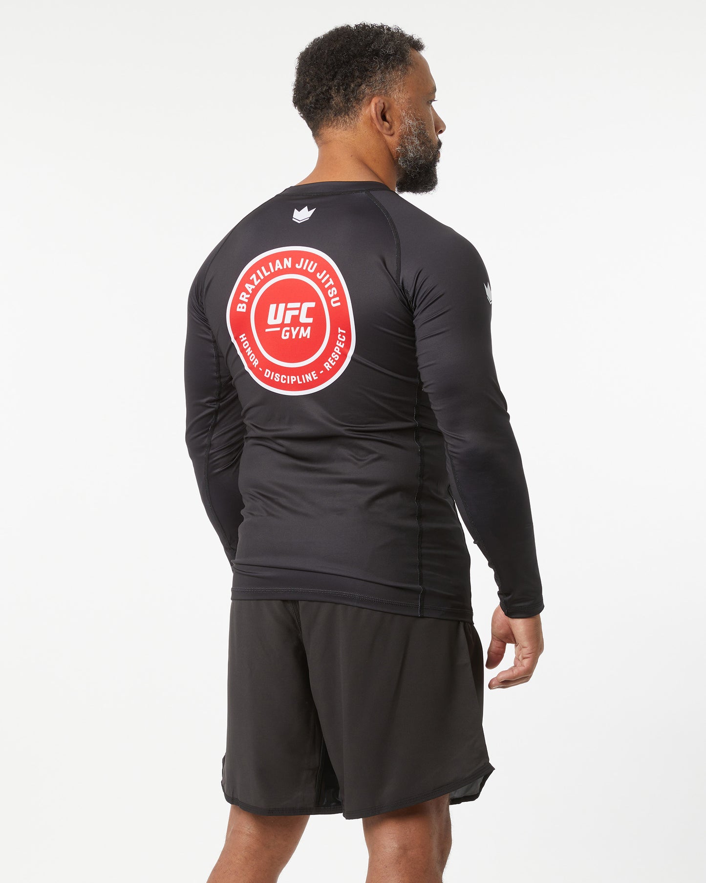 Person wearing a black athletic outfit with UFC Gym logo on the back against a white background facing backwards and slightly right