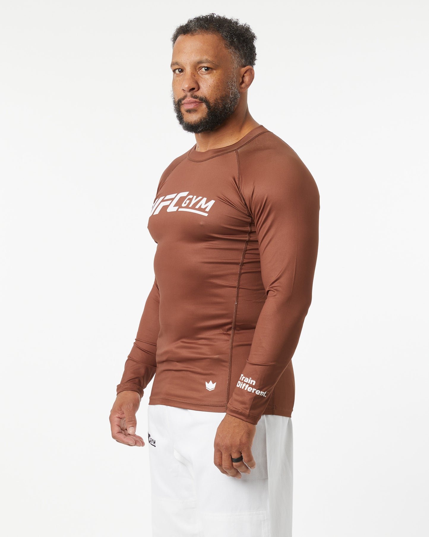 Man wearing a brown long-sleeve shirt with visible branding on a white background facing left