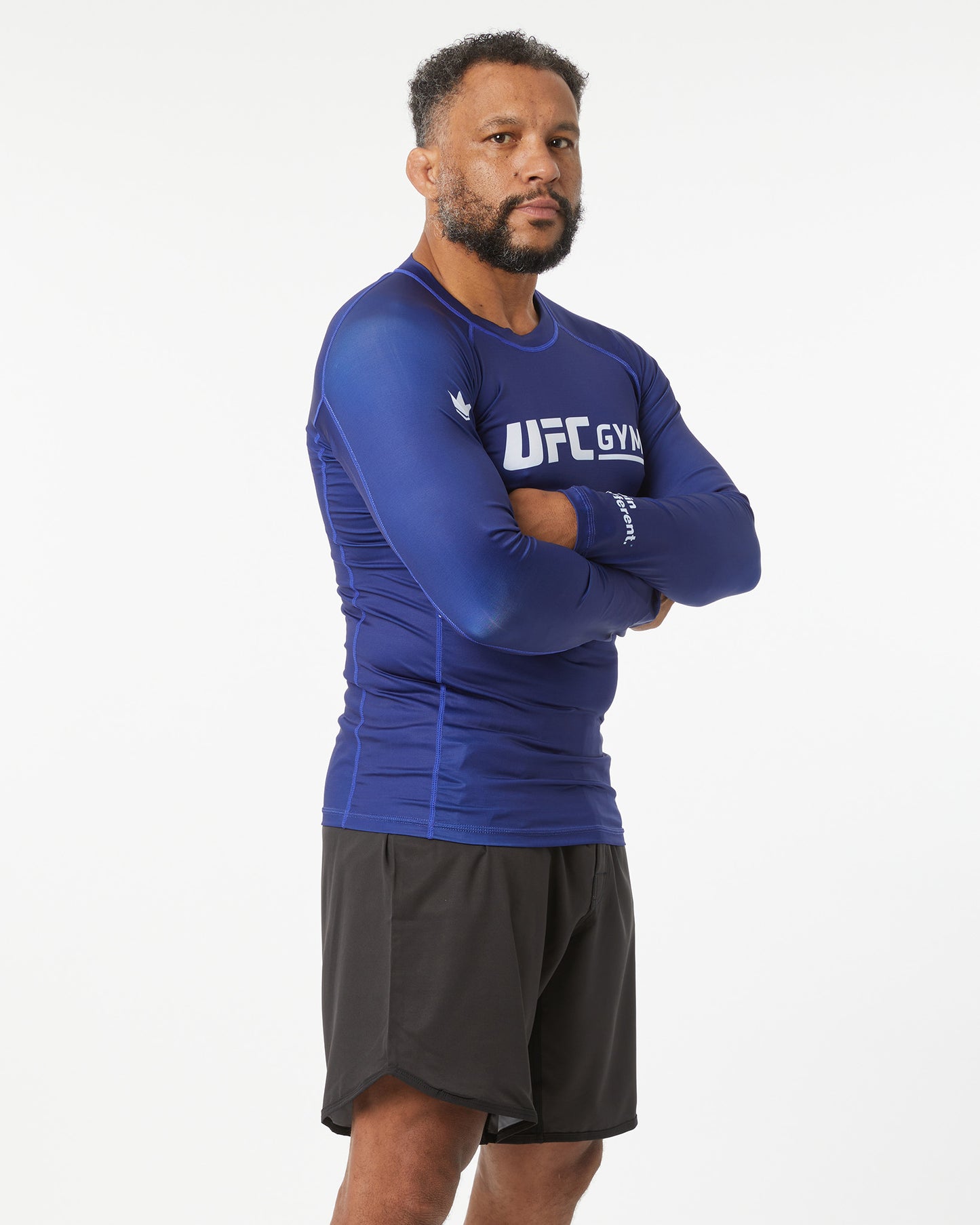 Man wearing a blue UFC Gym shirt and black shorts on a white background facing slightly right