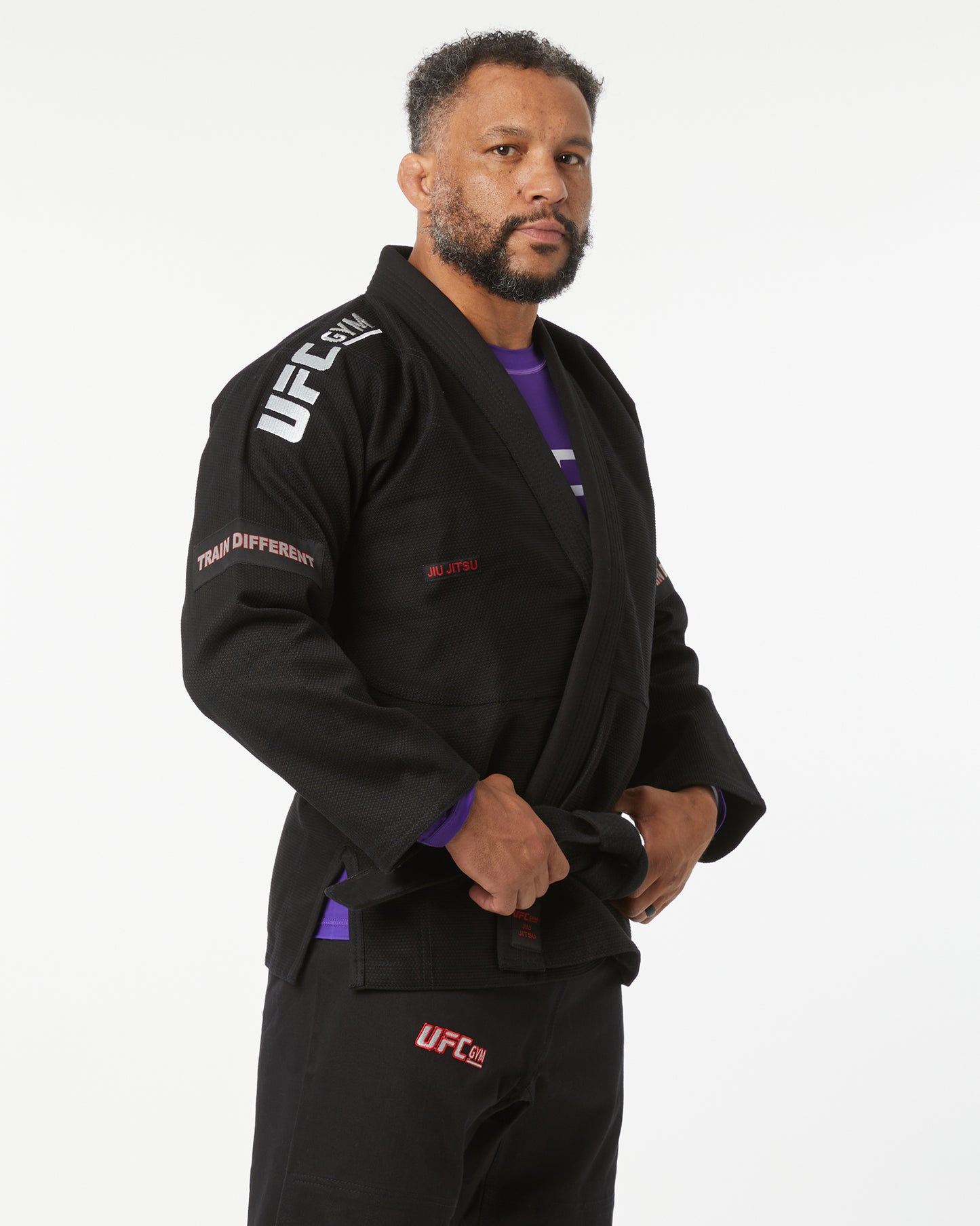 Person wearing a black UFC branded gi on a white background facing right looking forward