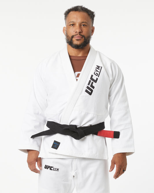 Man wearing a white UFC Gym kimono with a black belt on a white background facing forward