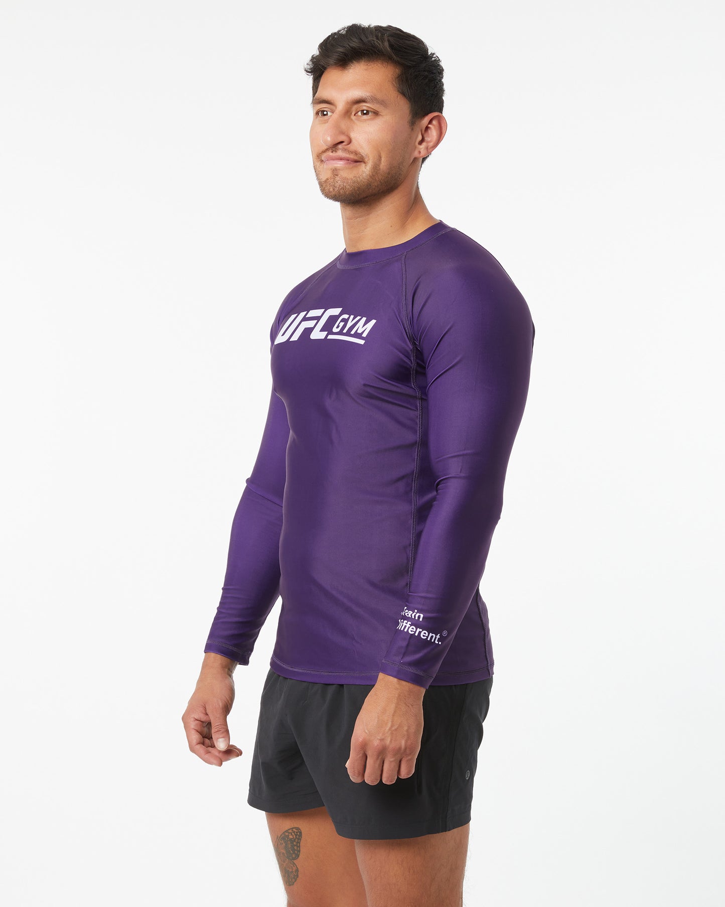 Man wearing a purple UFC Gym long-sleeve shirt on a white background facing left