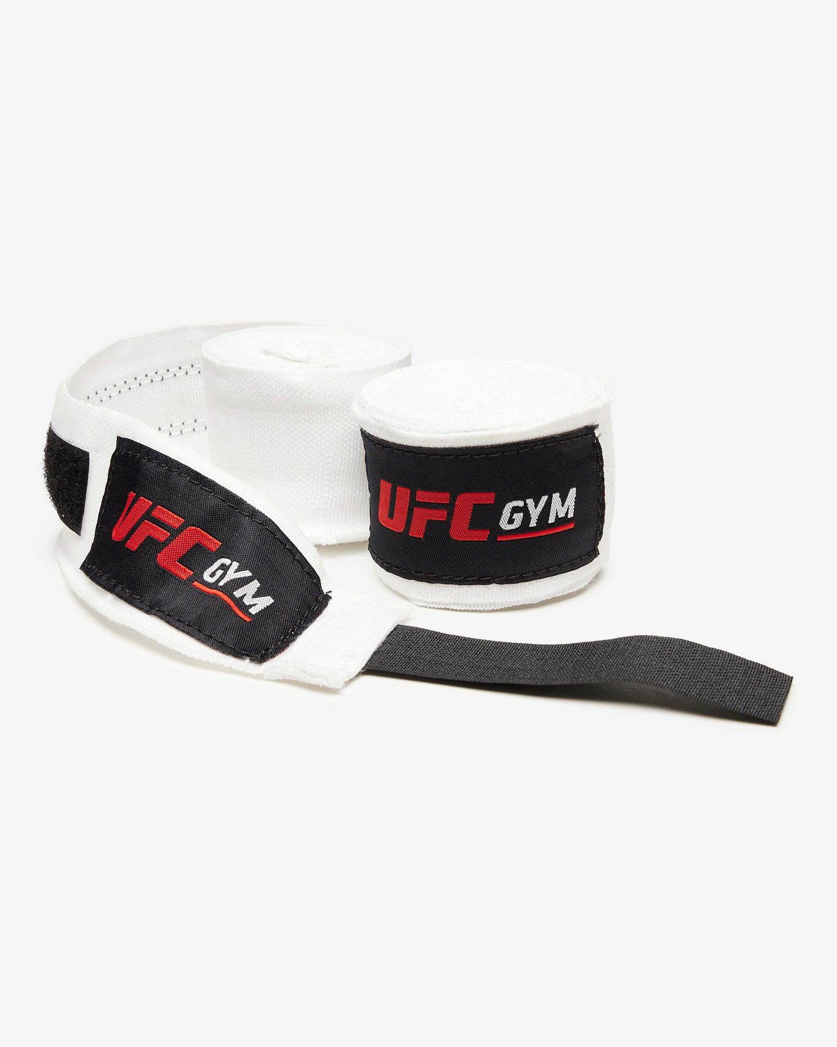 The TD 180 HAND WRAPS WHITE by UFC Gym feature black velcro straps and red-and-white UFC Gym logos, shown flat on a white background—ideal for mixed martial arts fighters.