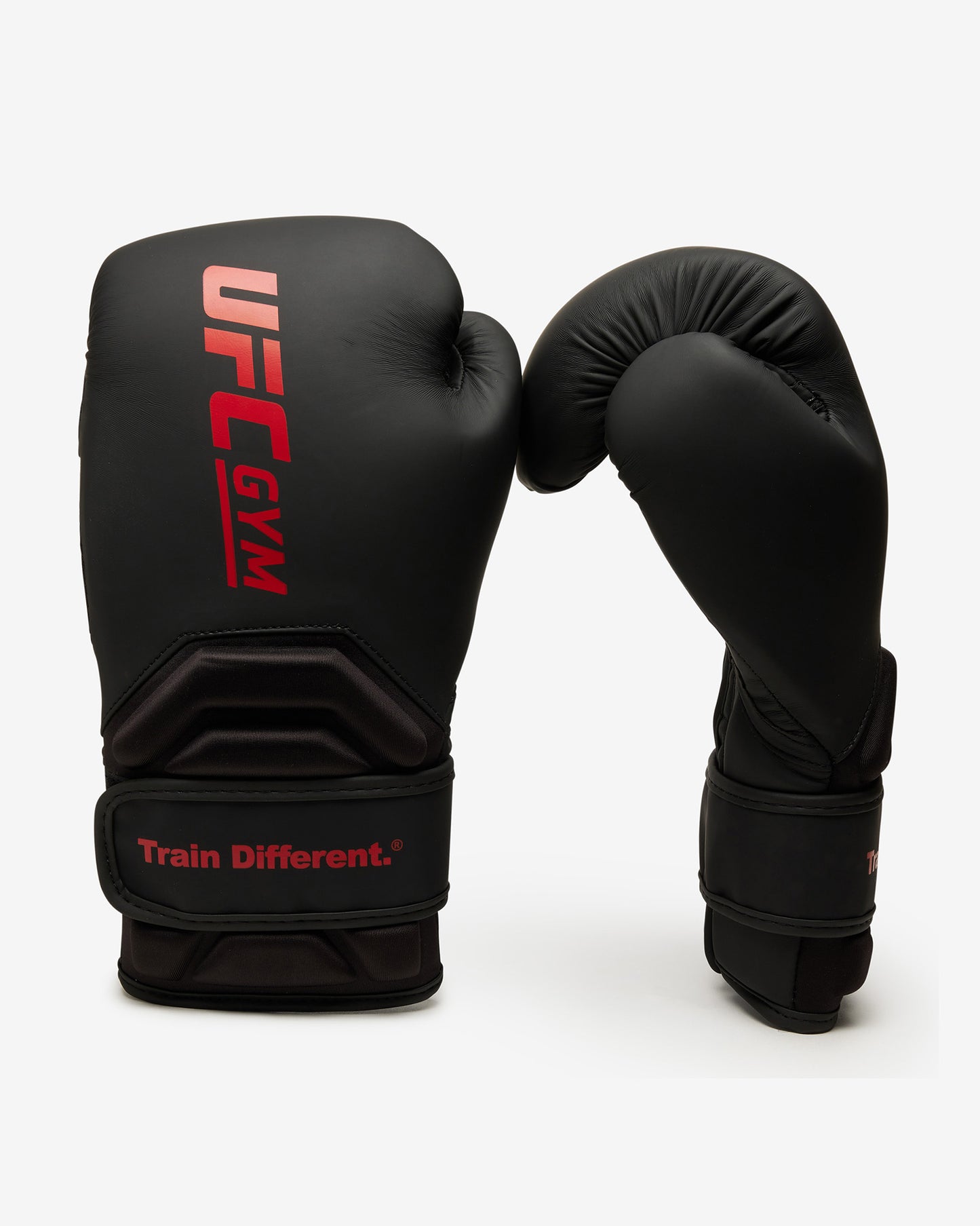 Two black TD ADULT BOXING GLOVE BLACK by UFC Gym stand upright on a white background. One glove features the red UFC Gym logo and Train Different. slogan; the other shows the palm, wrist straps, and protective design.