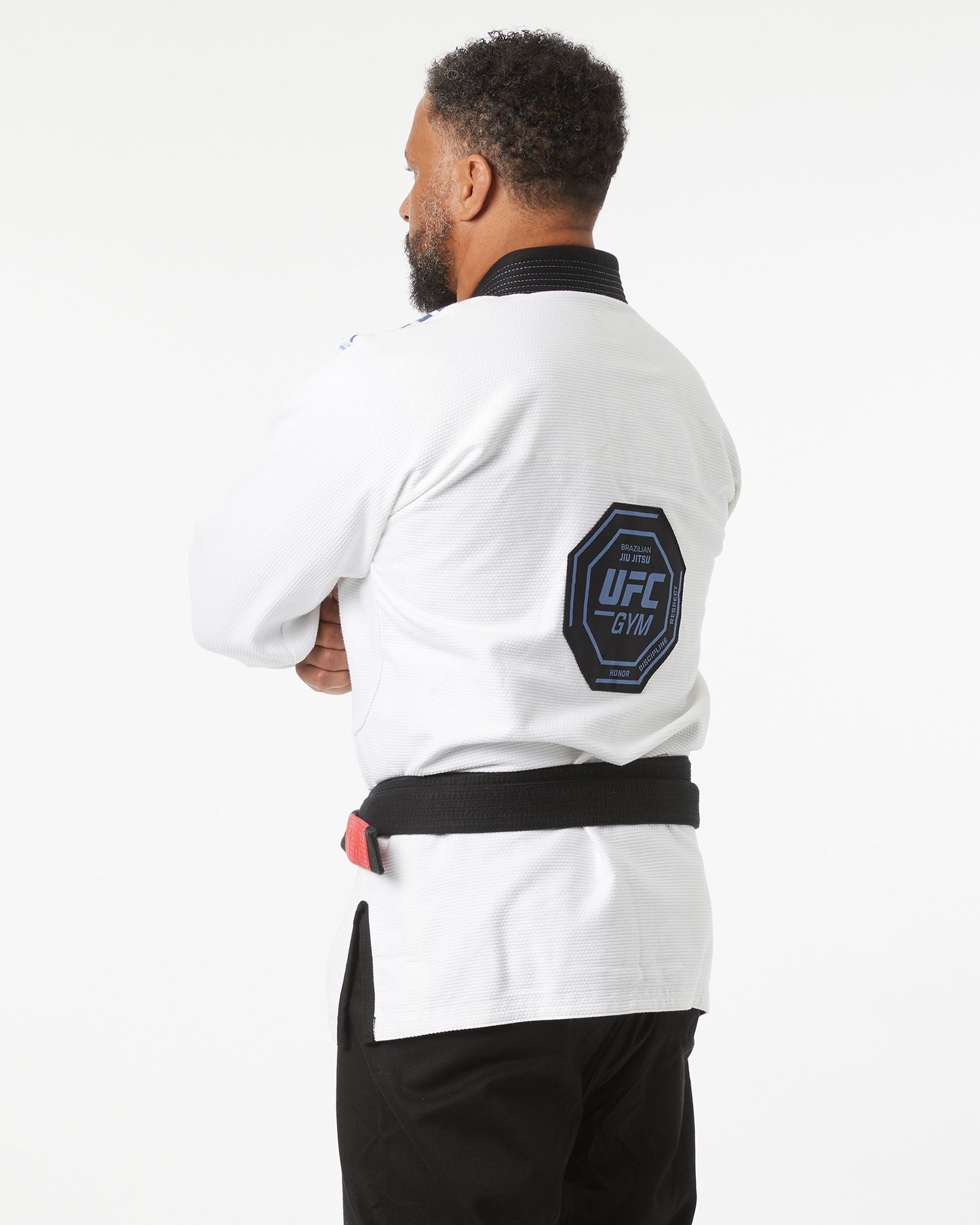 Person wearing a white UFC Gym jacket with a logo on the sleeve against a white background side slightly facing backwards