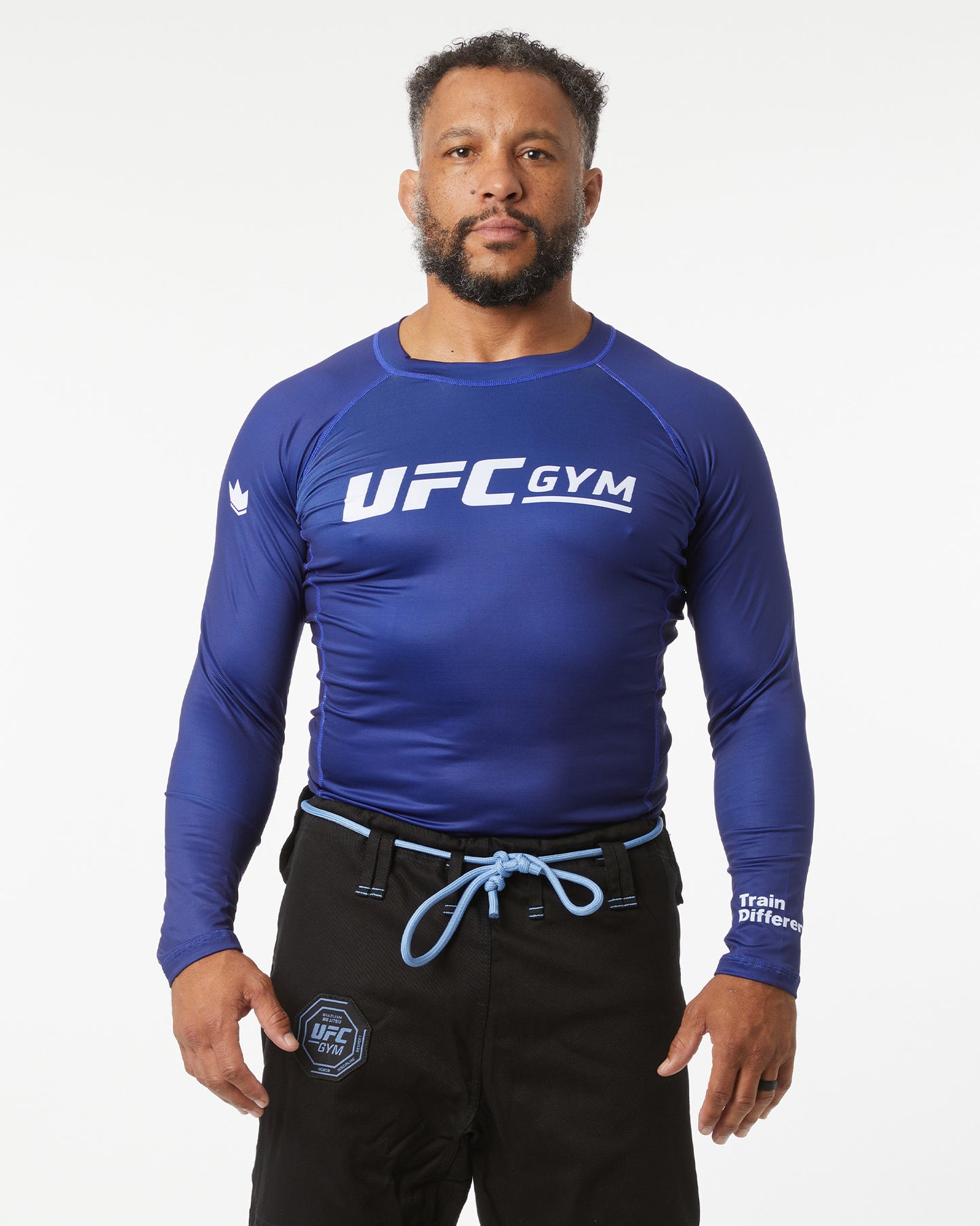 Person wearing a blue UFC Gym long-sleeve shirt on a white background arms not crossed