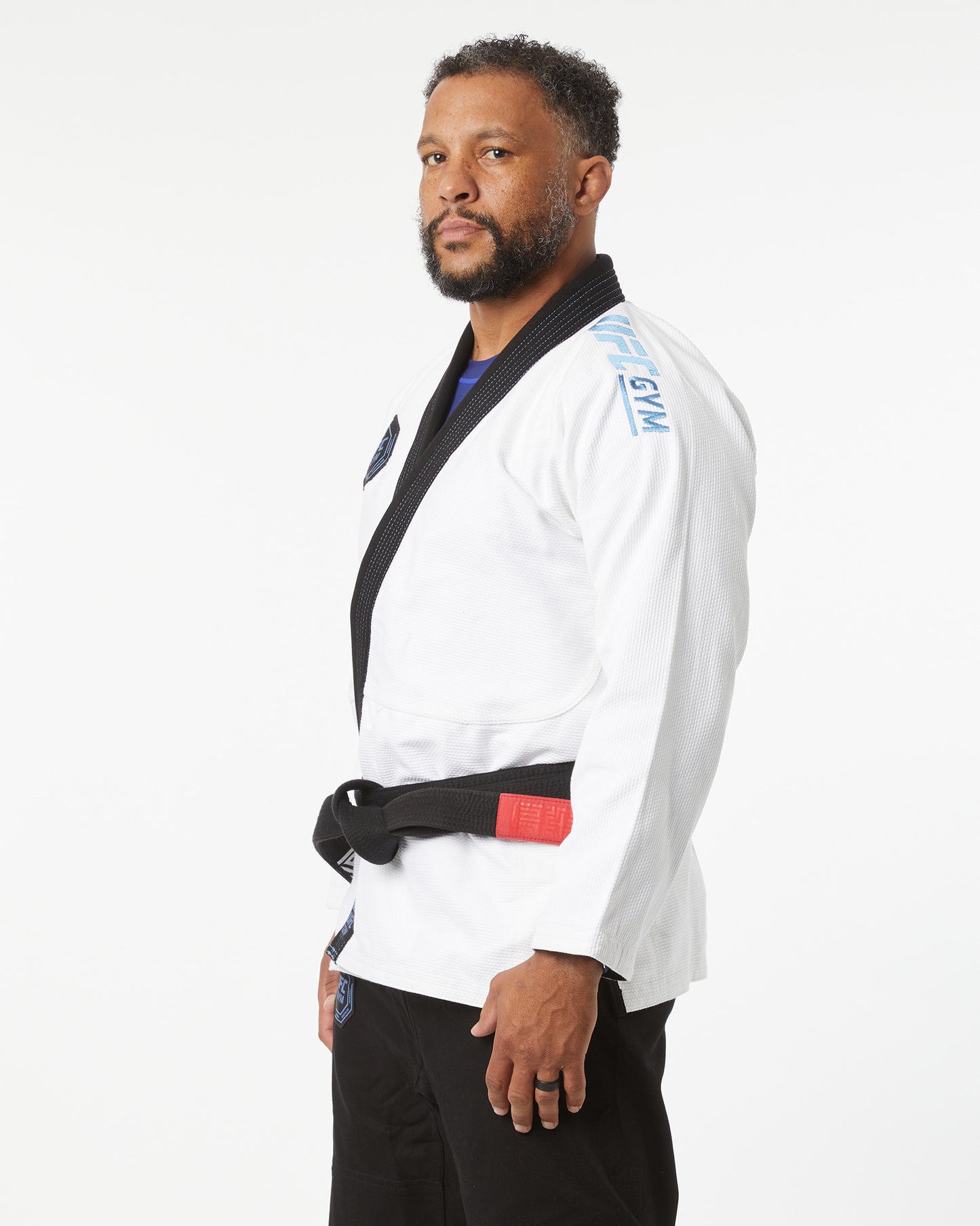 Man wearing a white martial arts uniform with a black belt on a white background facing slightly left