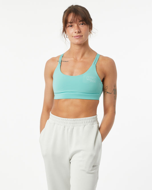 Woman wearing a light blue sports bra and white pants on a white background
