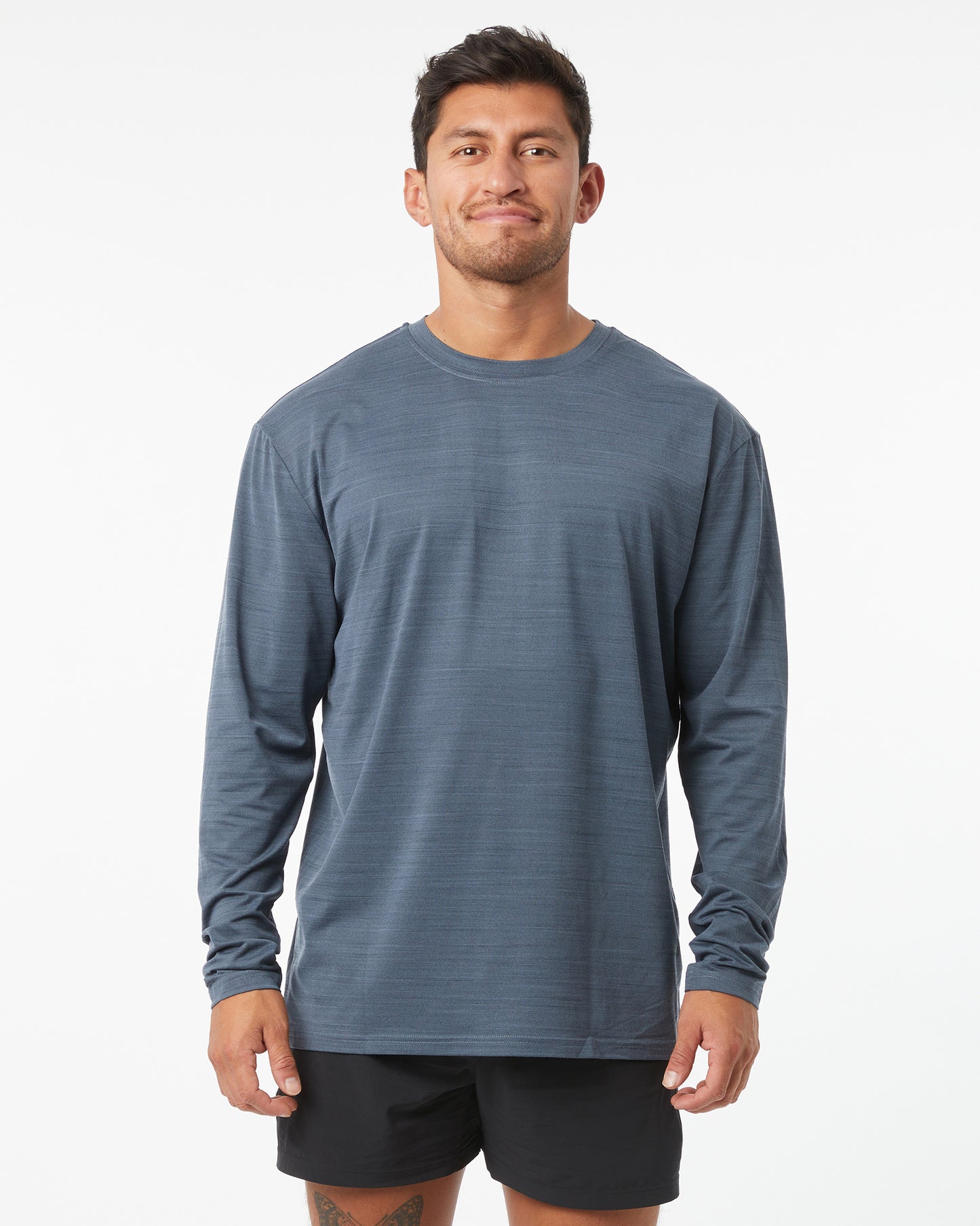 Man wearing a blue long-sleeve shirt and black shorts on a white background