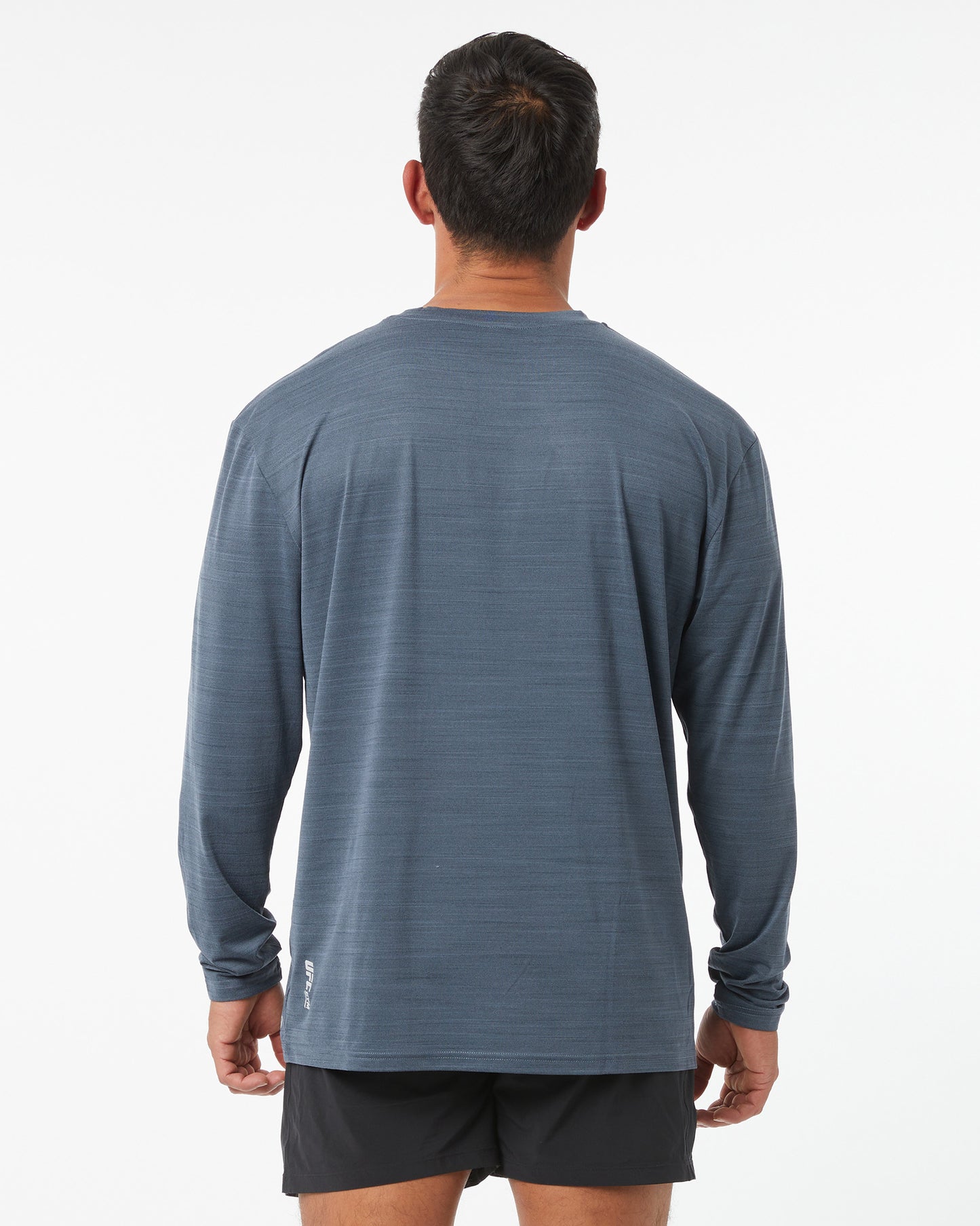Man wearing a blue long-sleeve shirt and black shorts on a white background