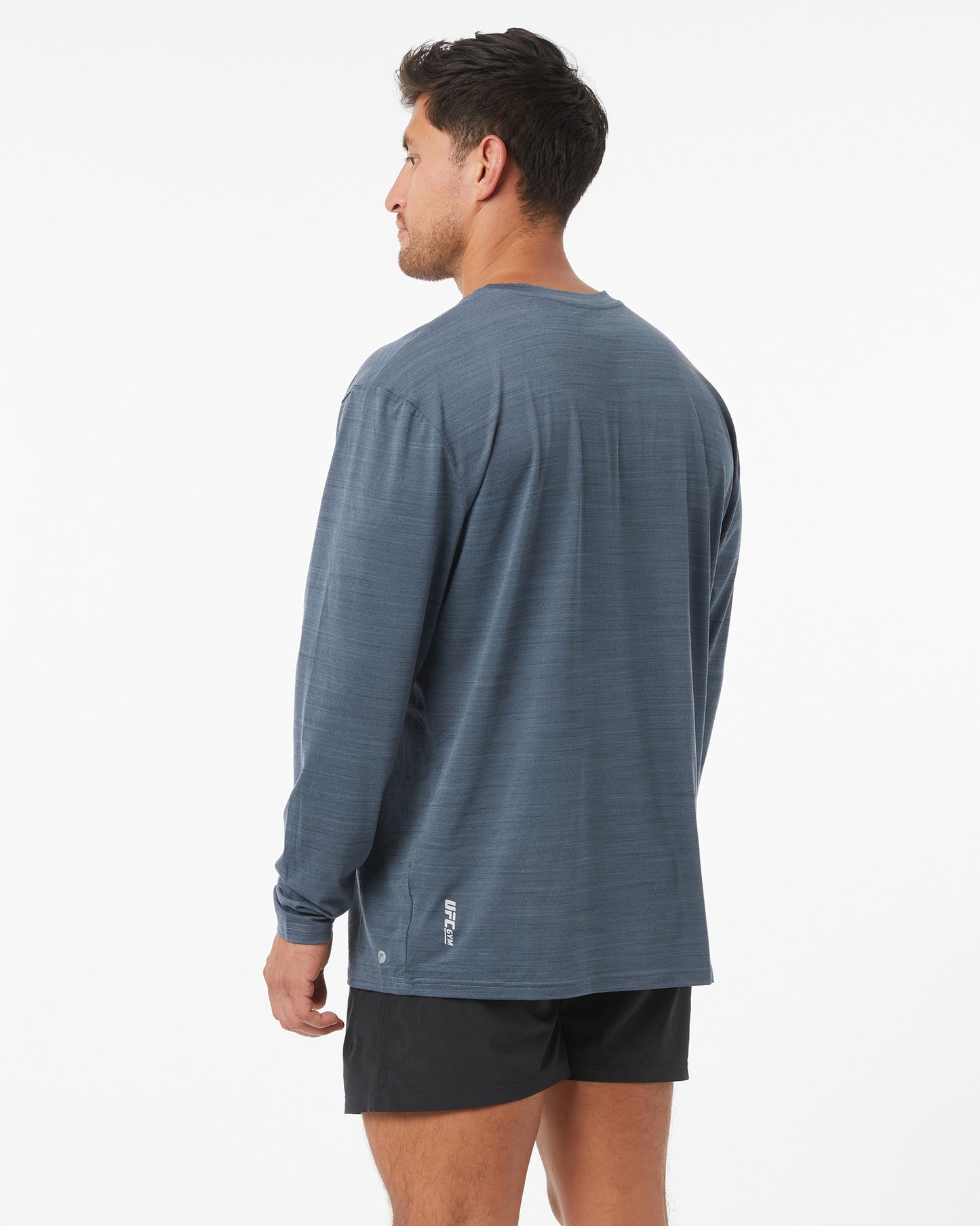 Man wearing a blue long-sleeve shirt and black shorts on a white background