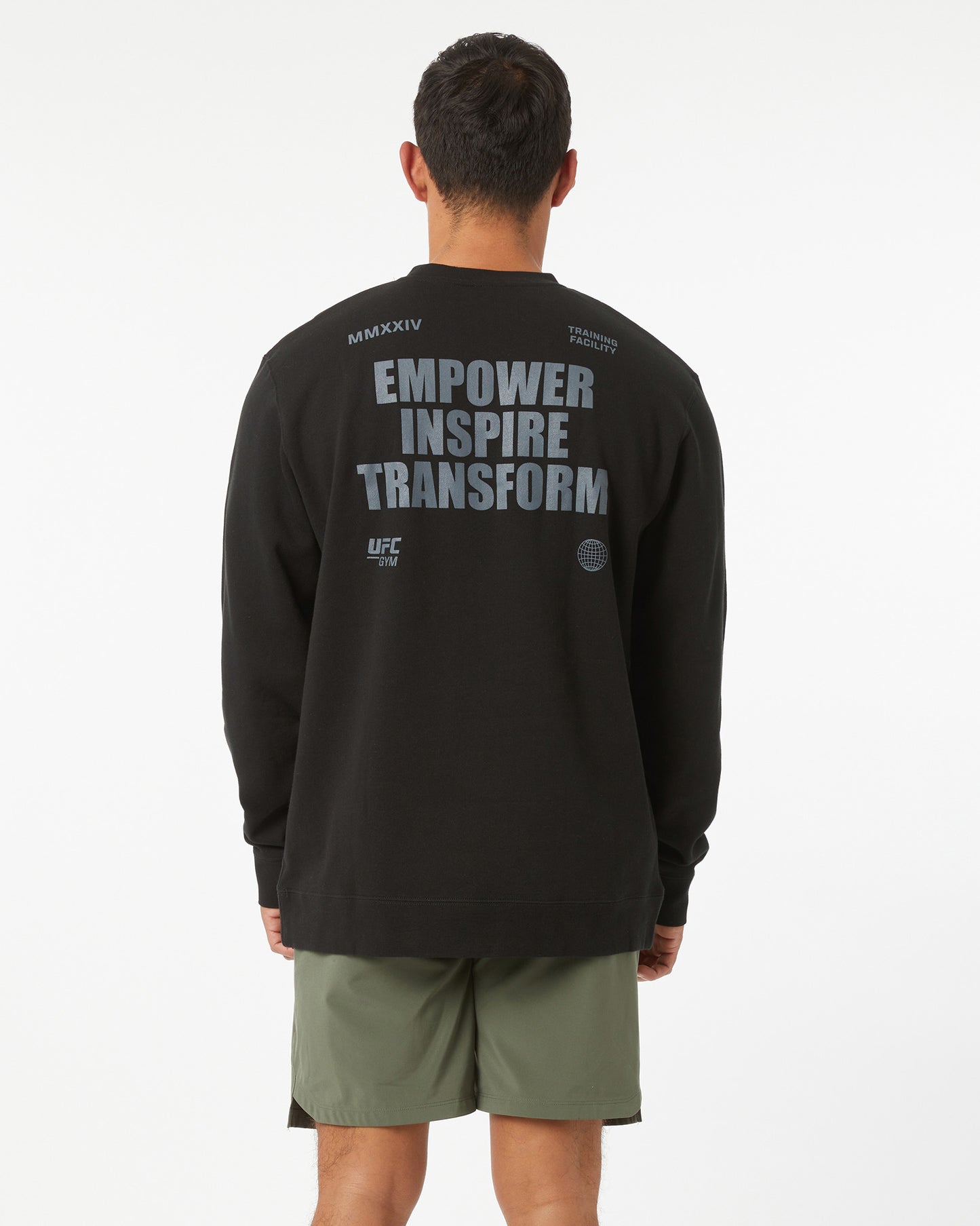 Person wearing a black long-sleeve shirt with text on the back, standing against a white background