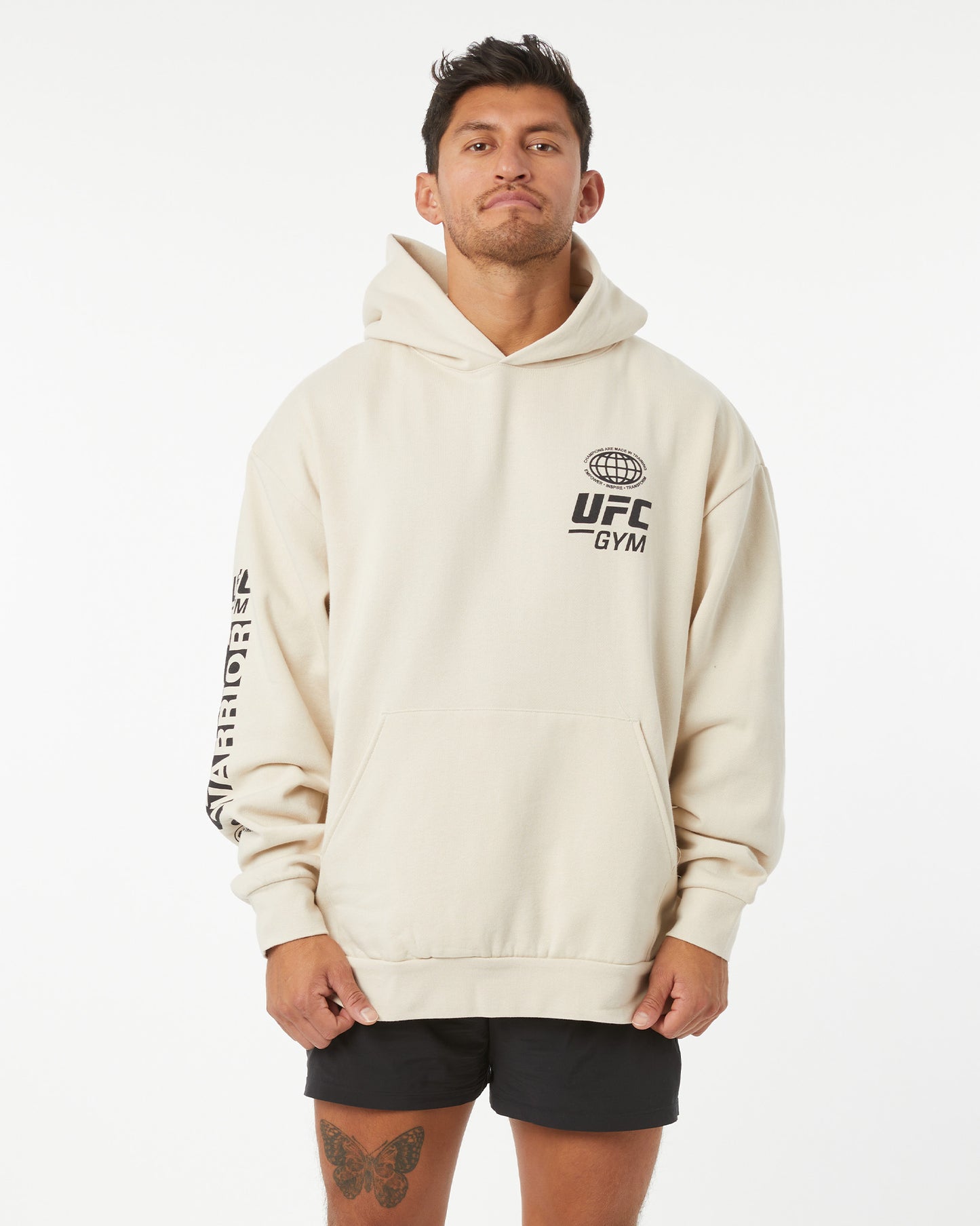 Man wearing a beige hoodie with UFC Gym logo on a white background