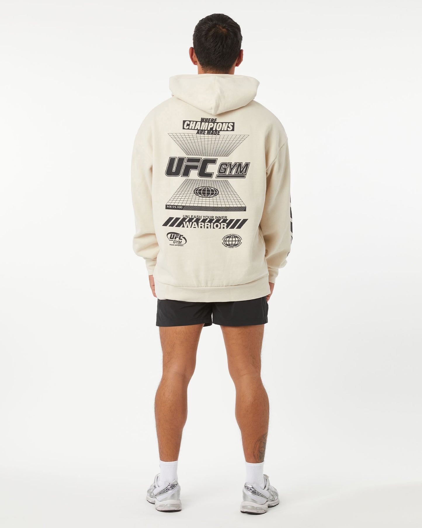 Person wearing a beige UFC Gym hoodie with branding on the back against a white background