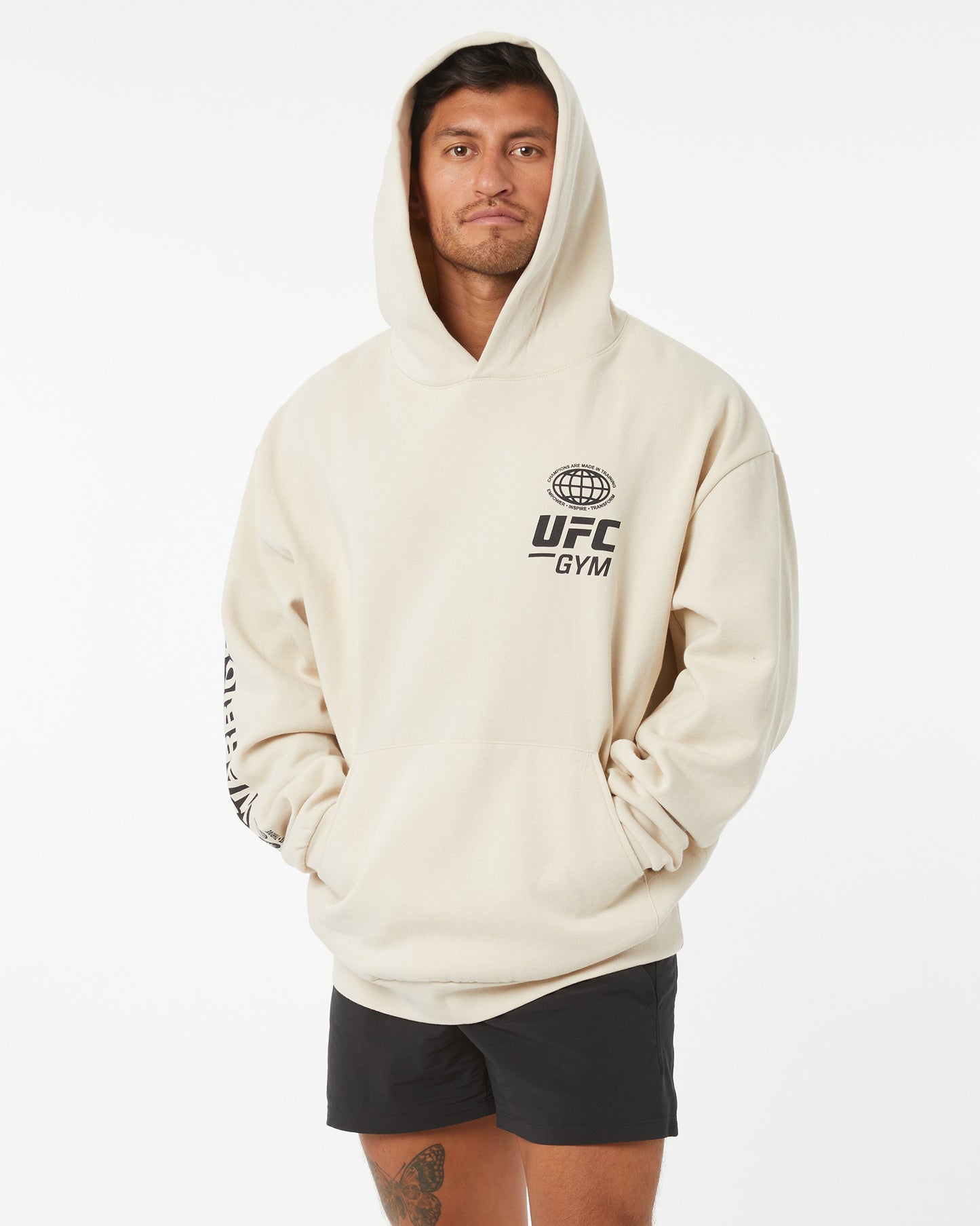 Person wearing a beige hoodie with UFC Gym logo on a white background