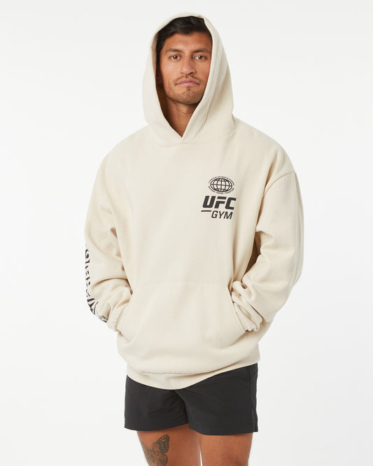 Person wearing a beige hoodie with UFC Gym logo on a white background