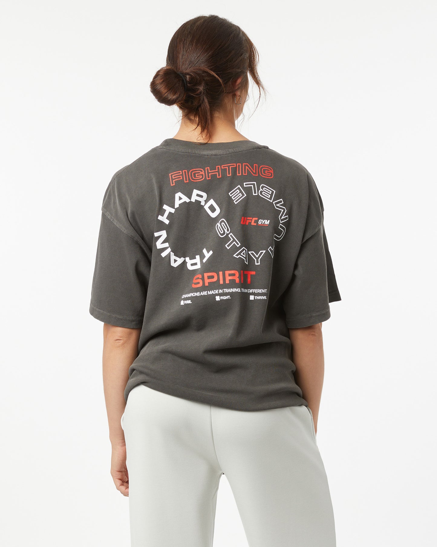Person wearing a dark gray t-shirt with text on the back, standing against a white background