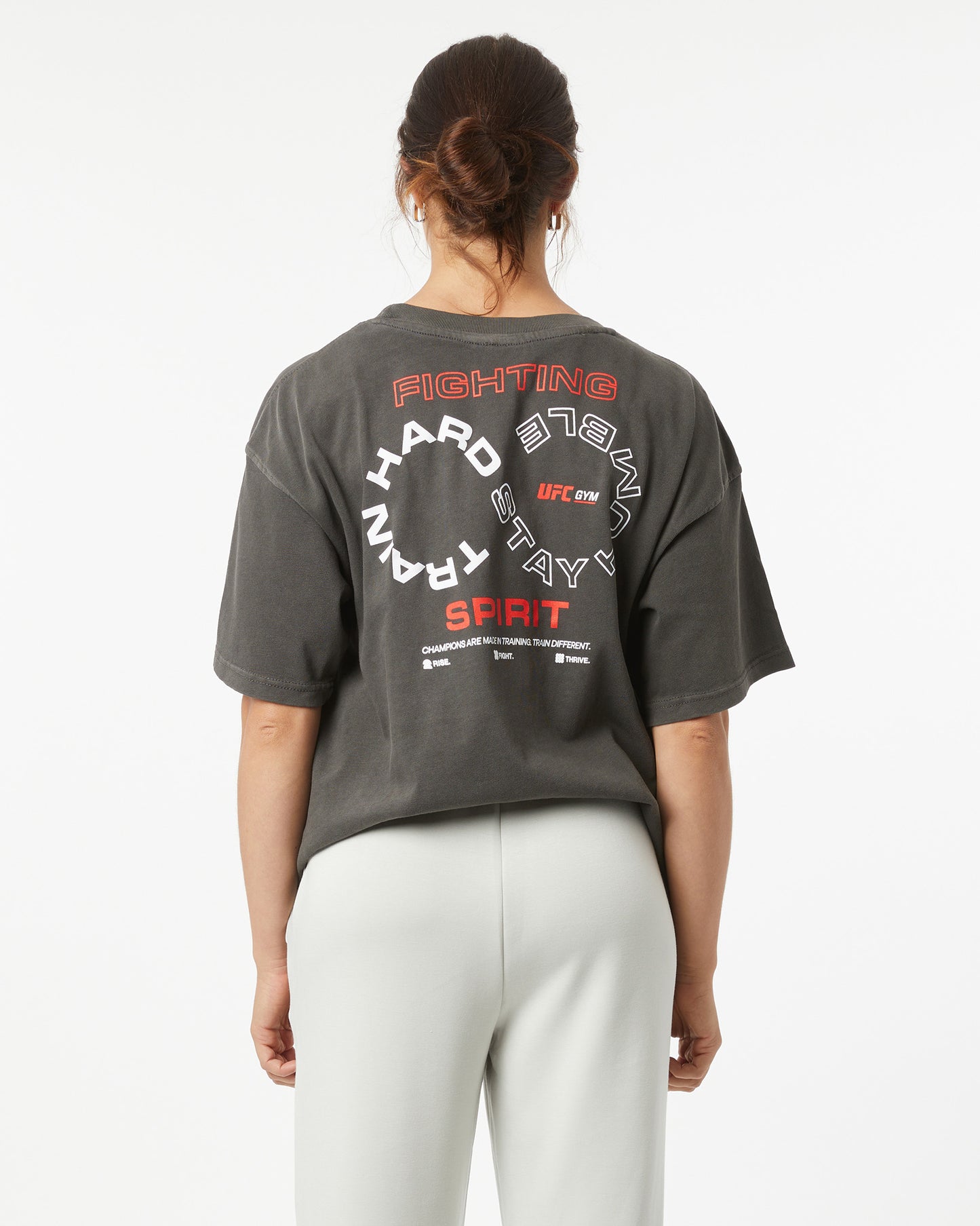 Person wearing a dark gray t-shirt with red and white text on the back, standing against a white background.