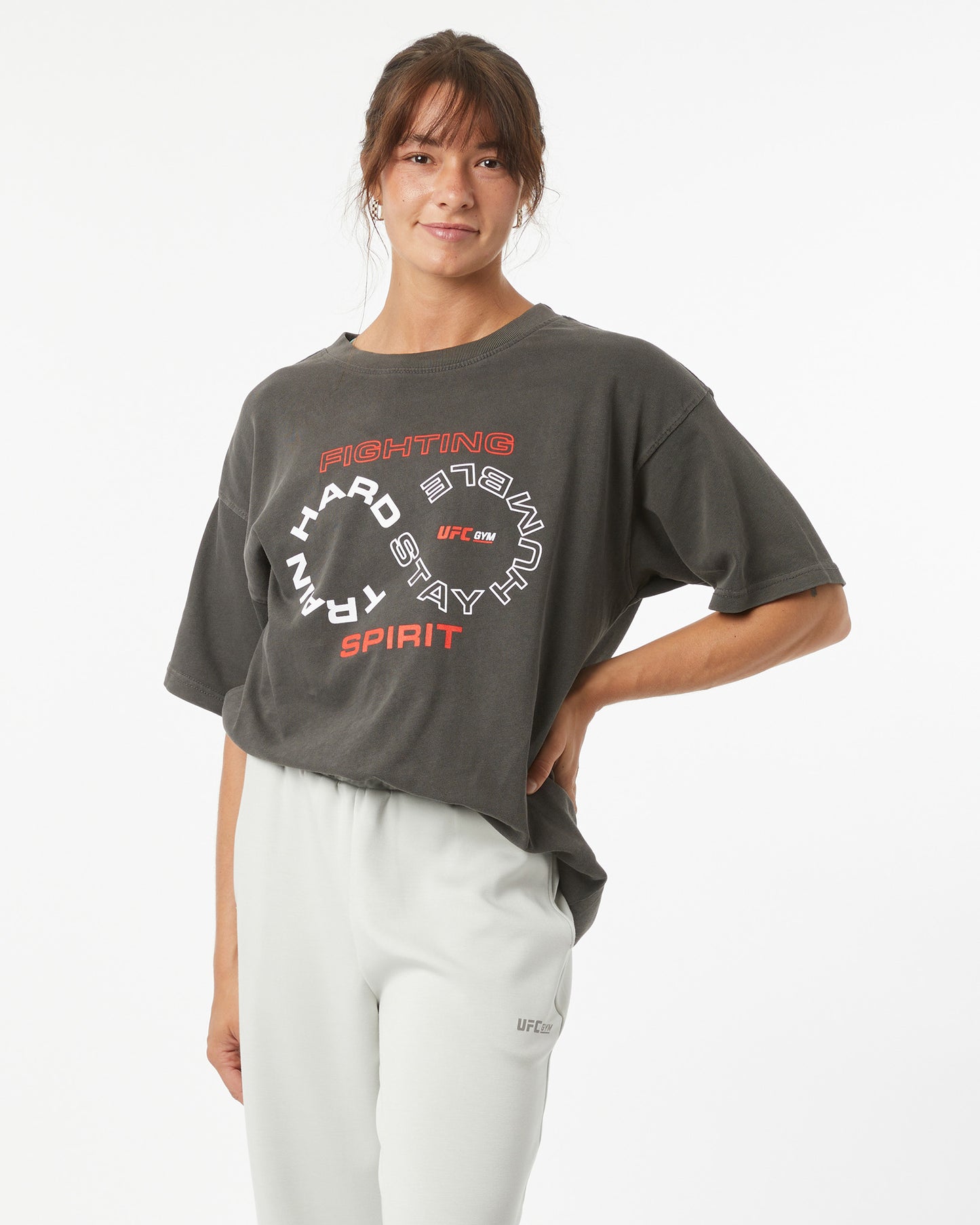 Person wearing a dark gray t-shirt with text and white pants on a light gray background
