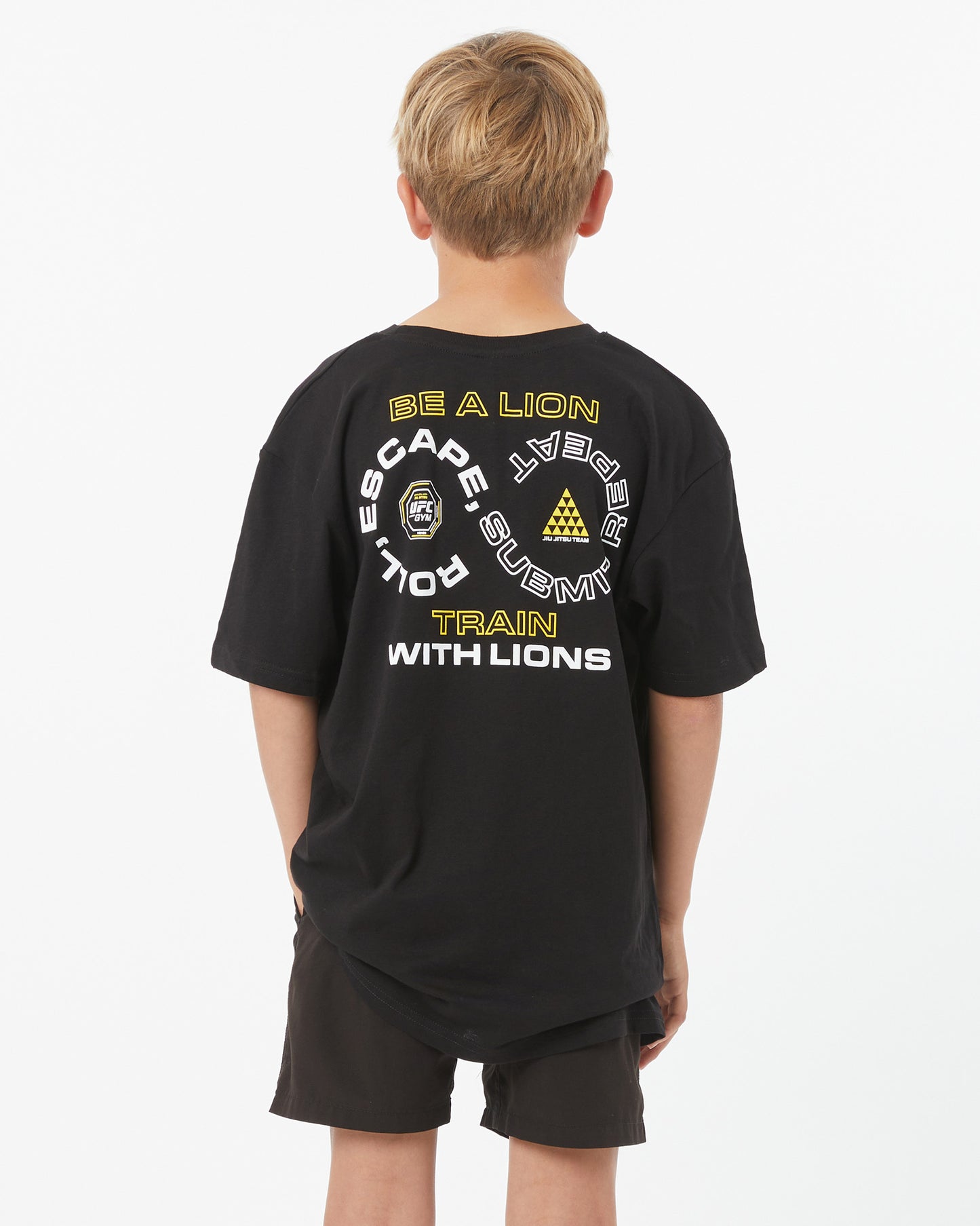 Child wearing a black t-shirt with text and logos on the back, standing against a white background