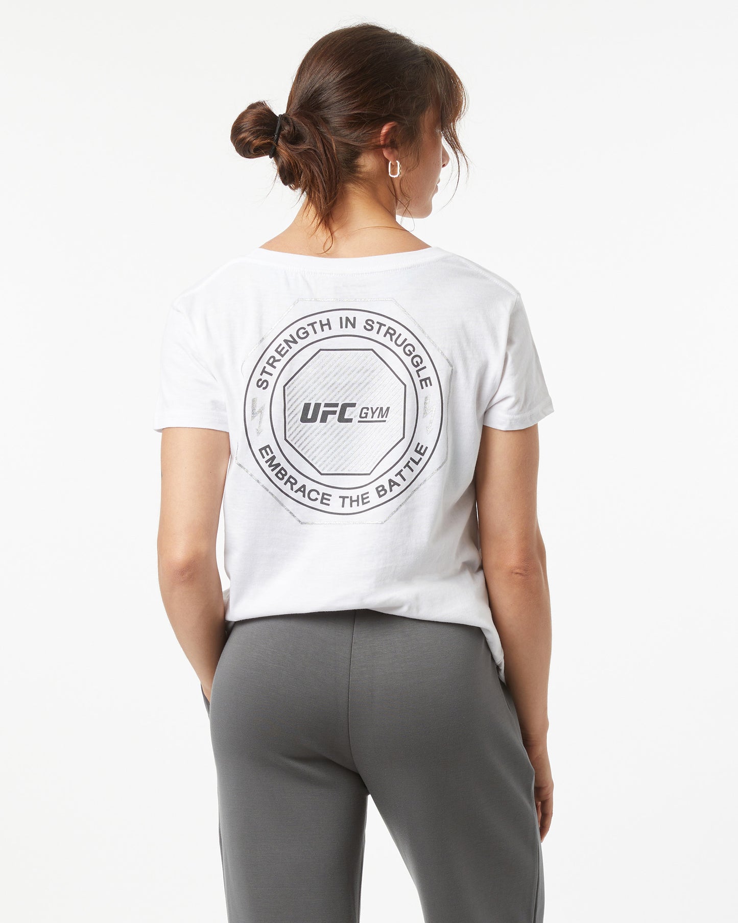 Person wearing a white UFC Gym t-shirt with text on the back, standing against a white background facing backwards