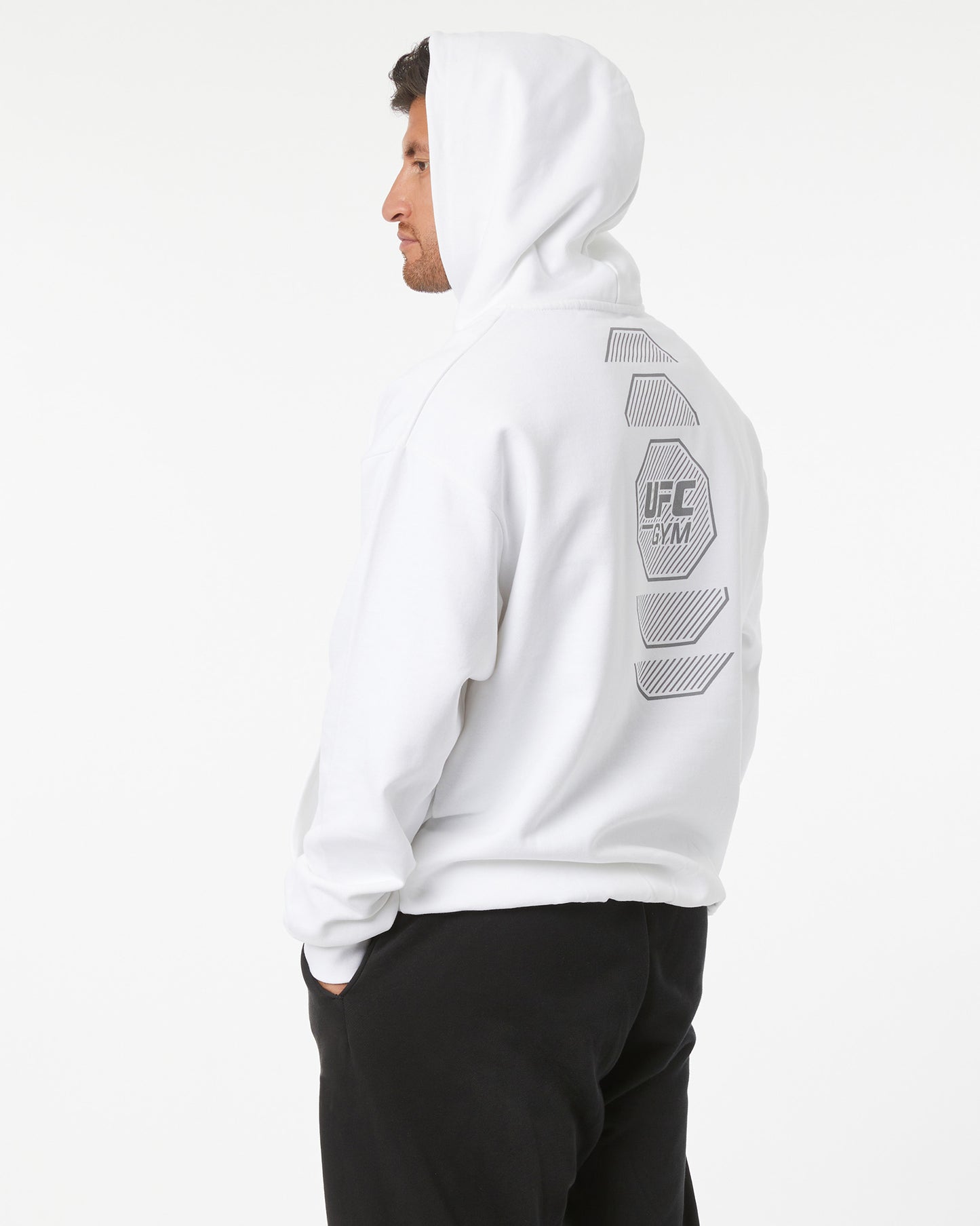 Person wearing a white hoodie with UFC branding on a light gray background facing left