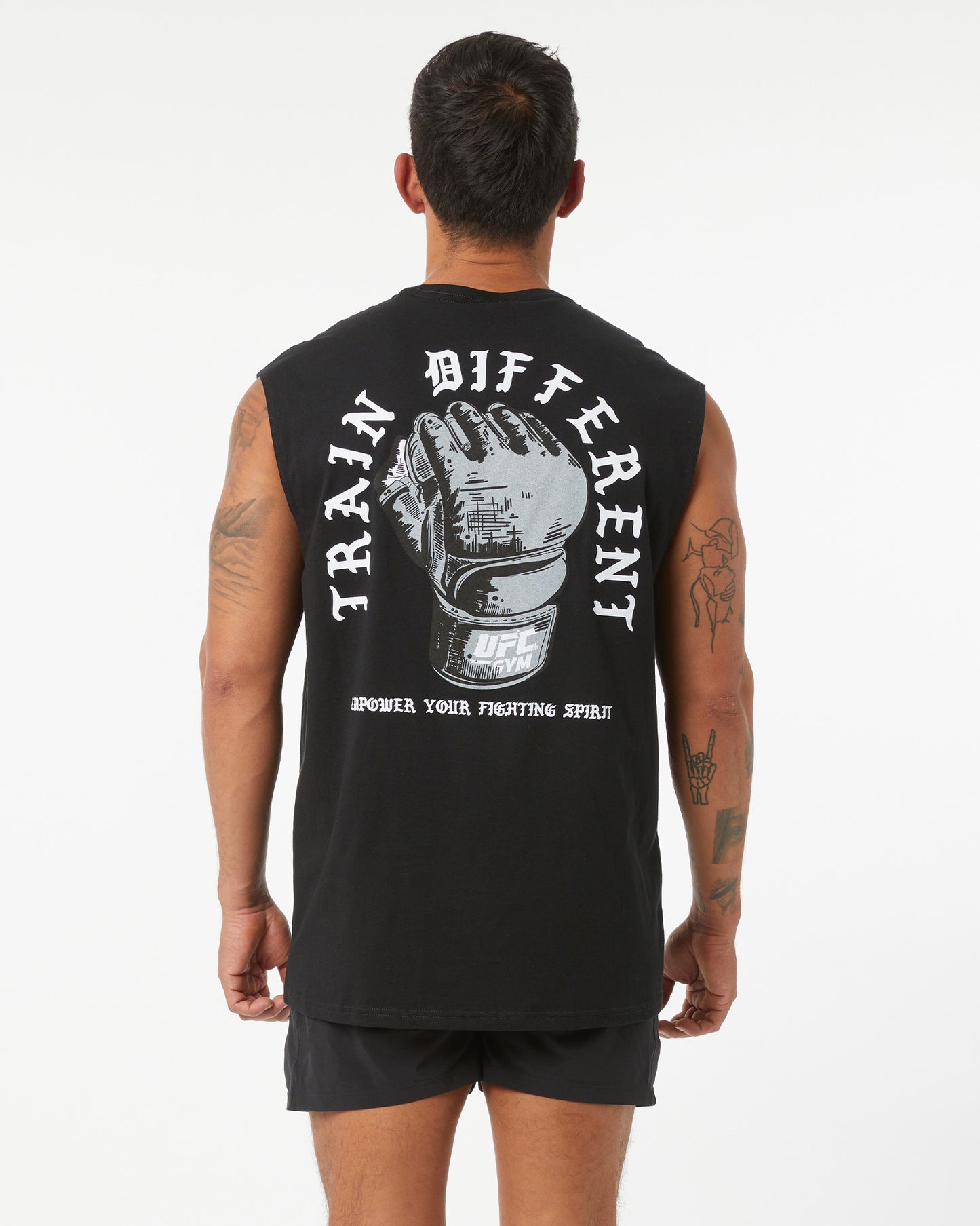 Person wearing a black sleeveless shirt with a graphic and text on the back, standing against a white background.