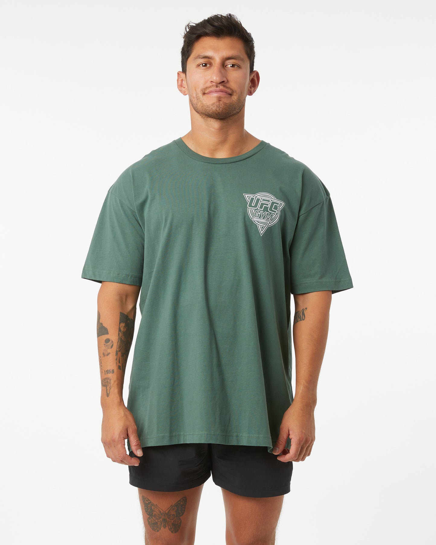 Man wearing a green t-shirt with a UFC GYM logo on a white background facing forward
