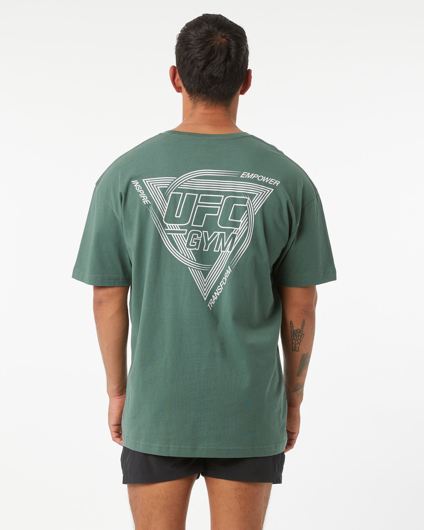 Person wearing a green UFC Gym t-shirt with branding on the back against a white background