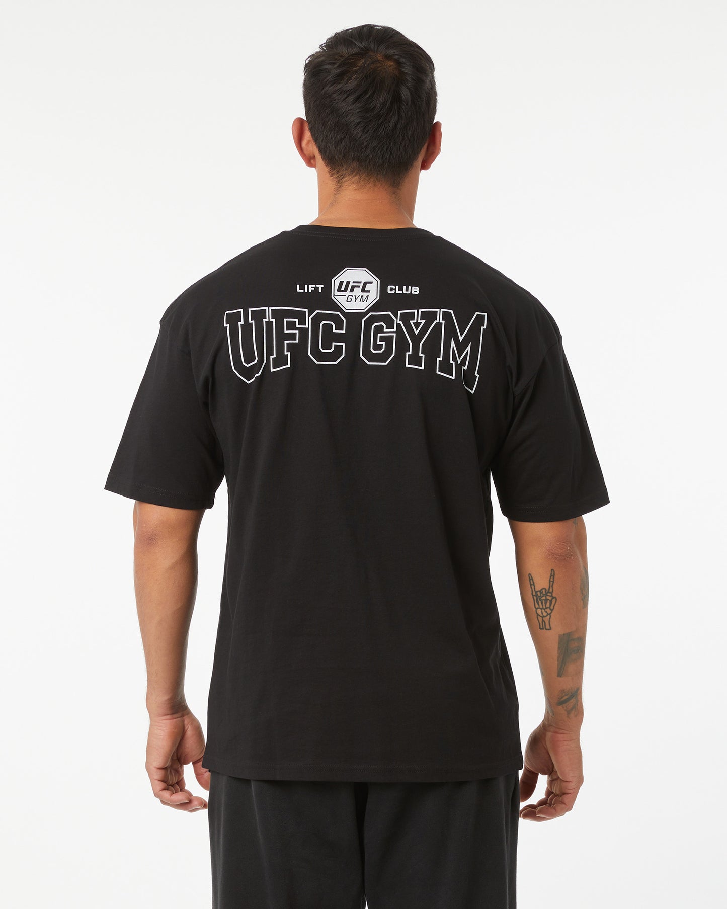 Person wearing a black UFC Gym t-shirt with branding on the back.