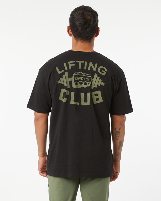 Person wearing a black t-shirt with 'Lifting Club' text and logo on the back, standing against a white background.