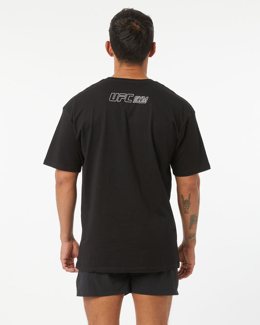 Person wearing a black UFC t-shirt with logo on the back against a white background