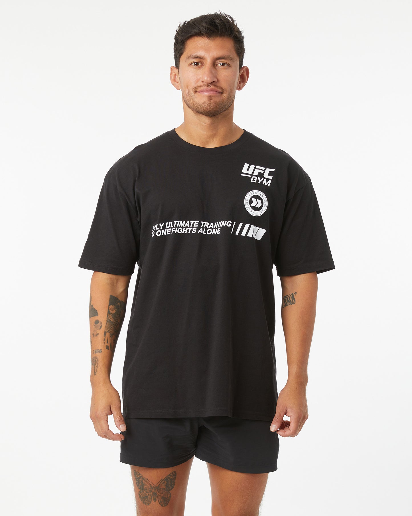 Man wearing black t-shirt with UFC GYM logo that says "only ultimate training no one fights alone" facing forward on a white background