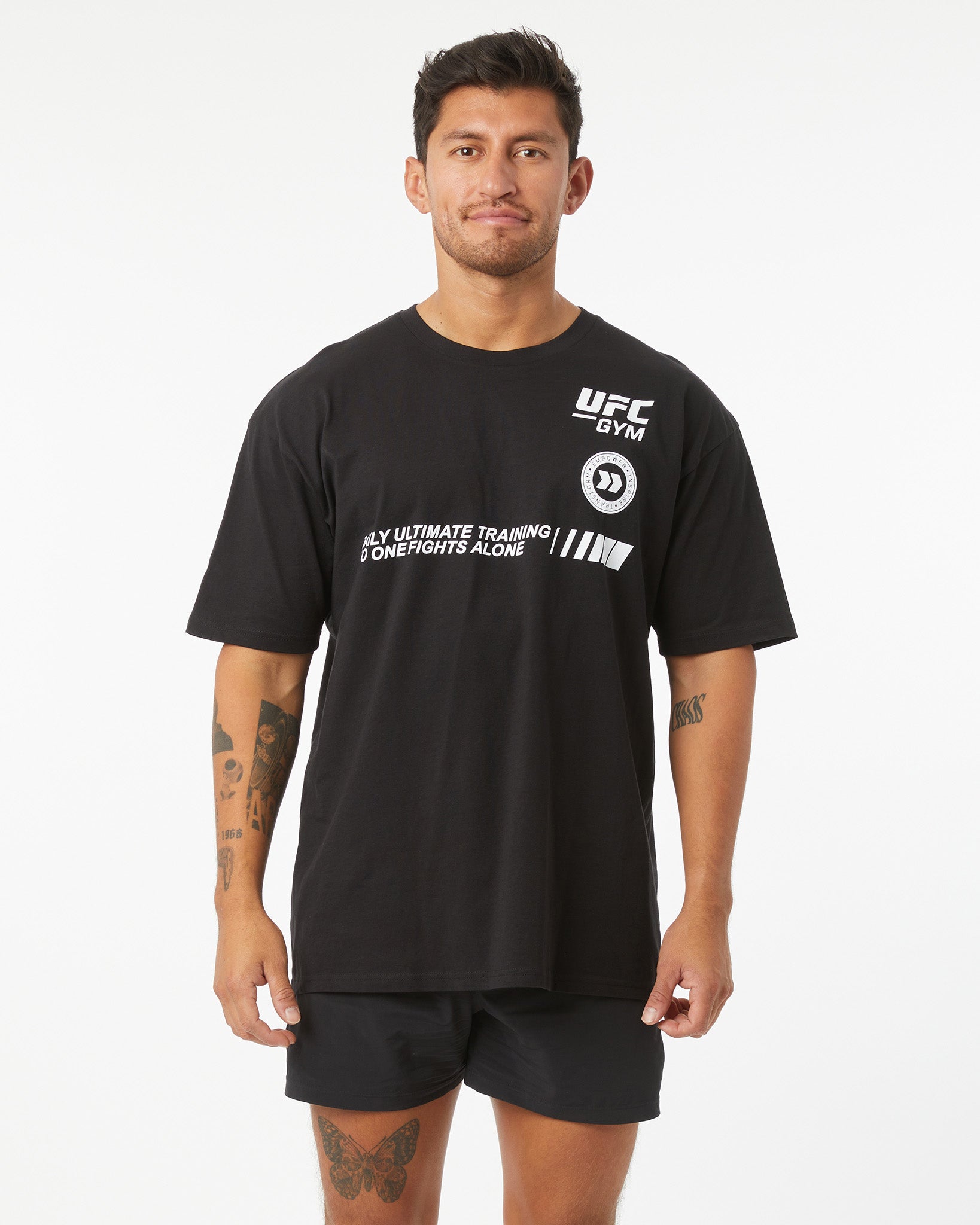Man wearing black t-shirt with UFC GYM logo that says "only ultimate training no one fights alone" facing forward on a white background