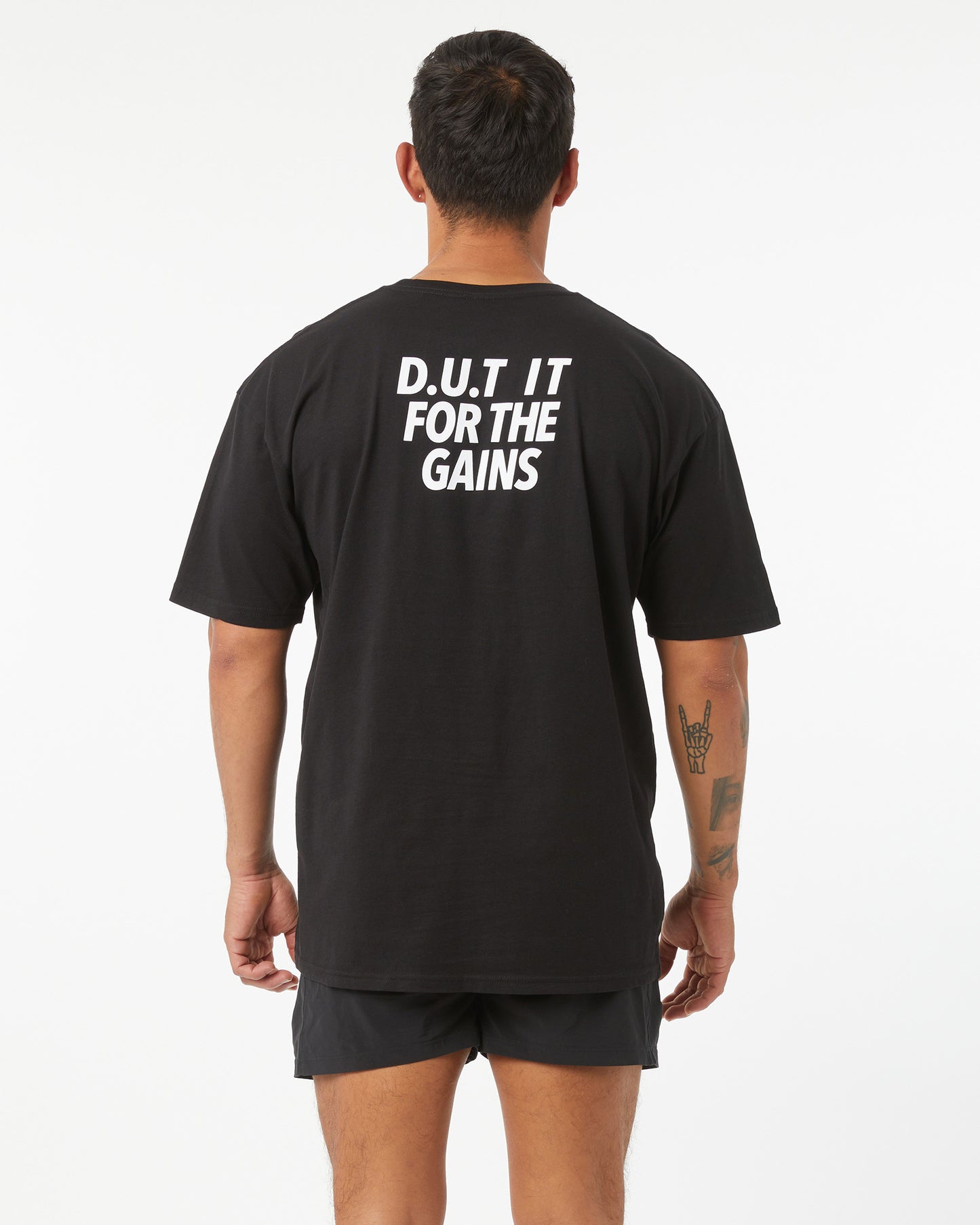Person wearing a black t-shirt with 'D.U.T. IT FOR THE GAINS' text on the back.