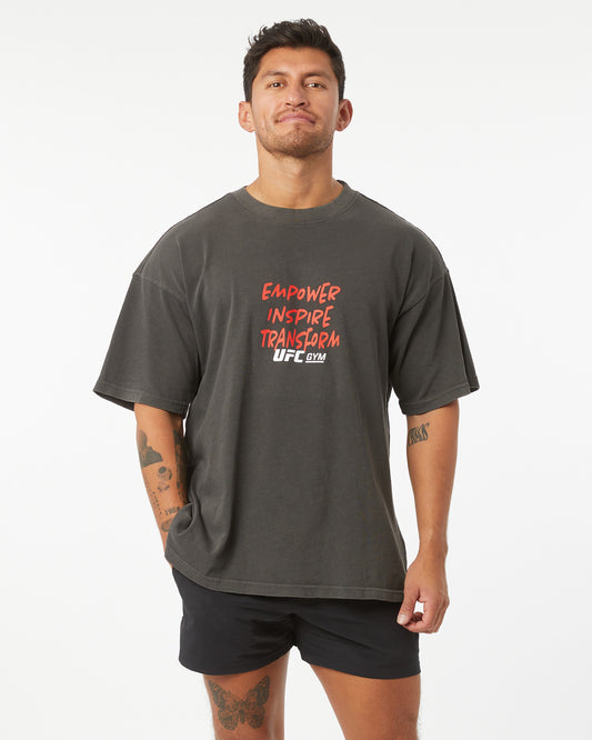 Man wearing a dark gray t-shirt with red and white text on a white background