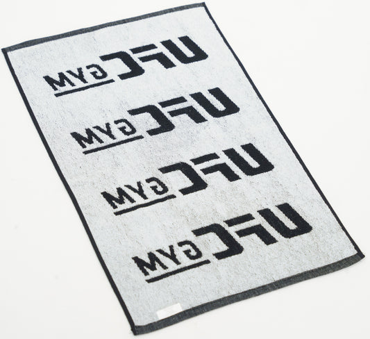 The KO WORKOUT TOWEL by UFC Gym is a rectangular white hand towel with four black UFC Gym logos in rows, each rotated 180°, and a black border. Laid flat, its ideal for your gym bag or workouts on-the-go.