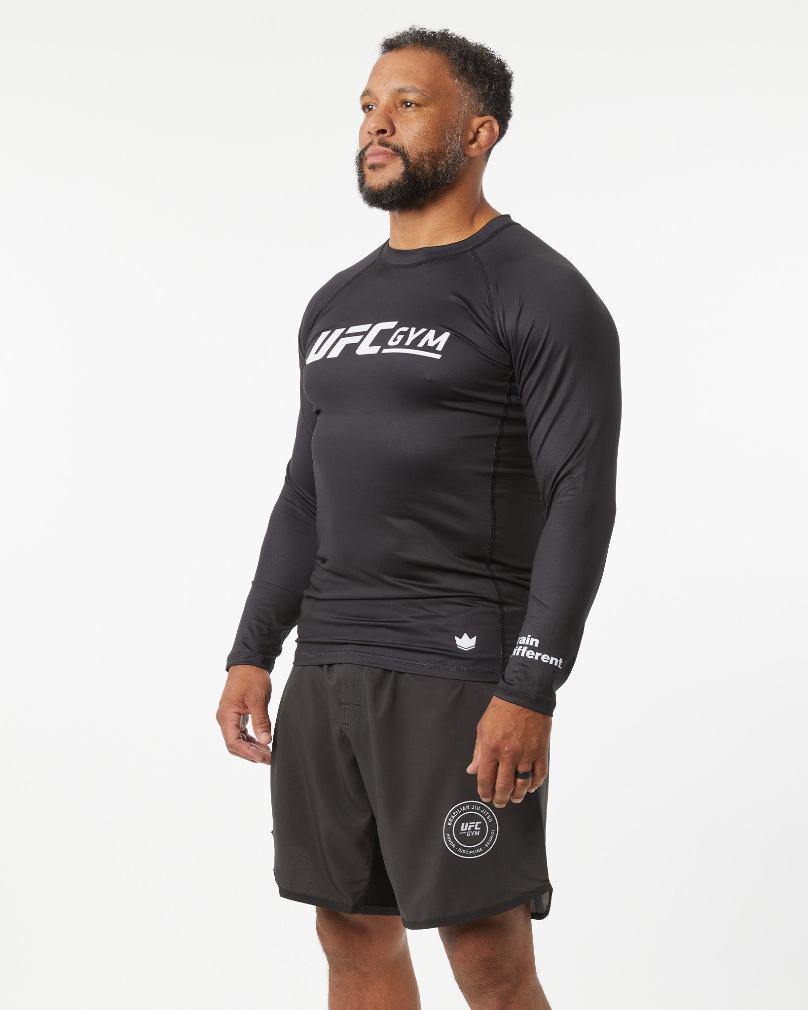 Person wearing a black UFC Gym long-sleeve shirt and shorts on a white background in a right-facing angle