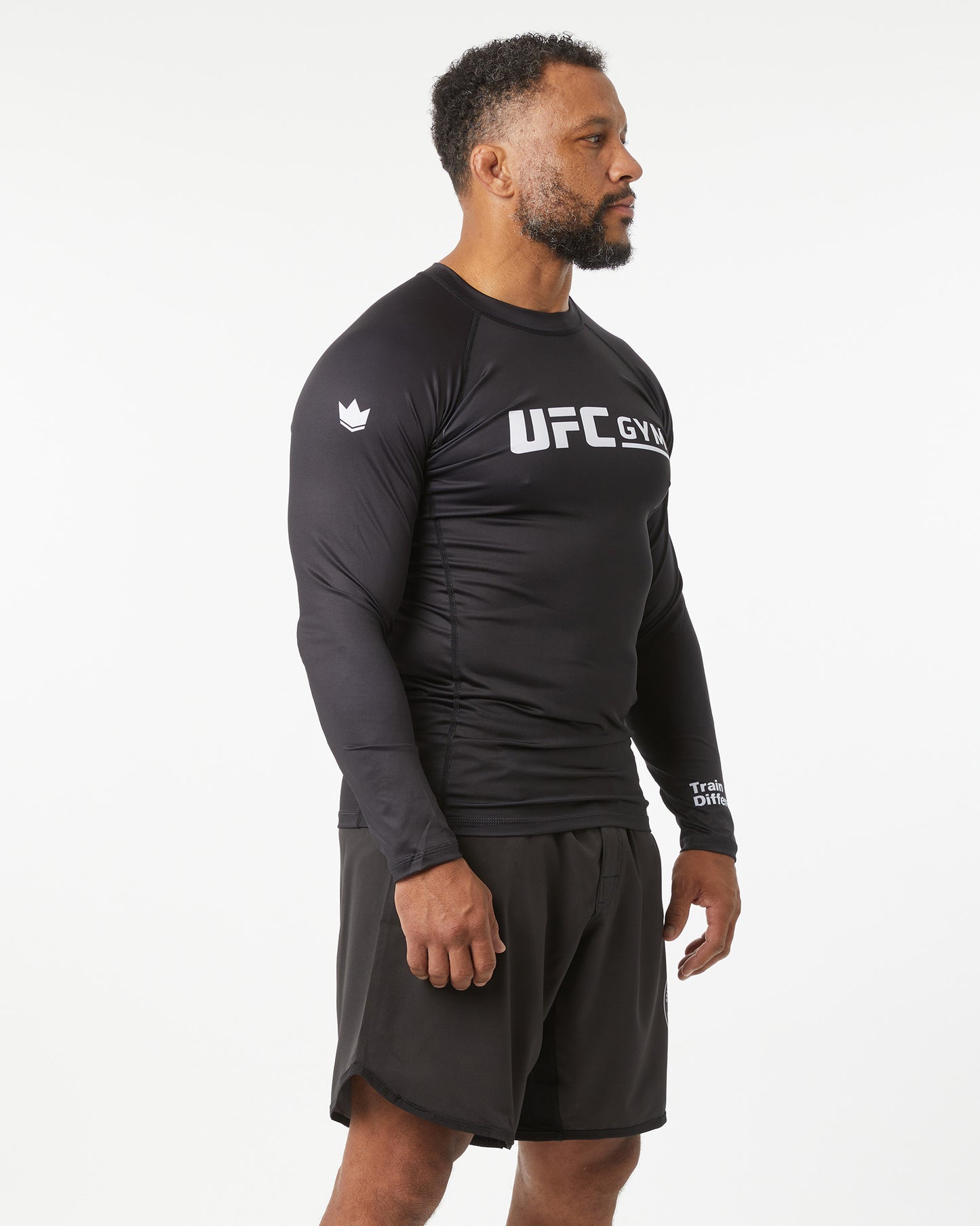 Man wearing a black UFC Gym long-sleeve shirt and shorts on a white background in a left-facing angle