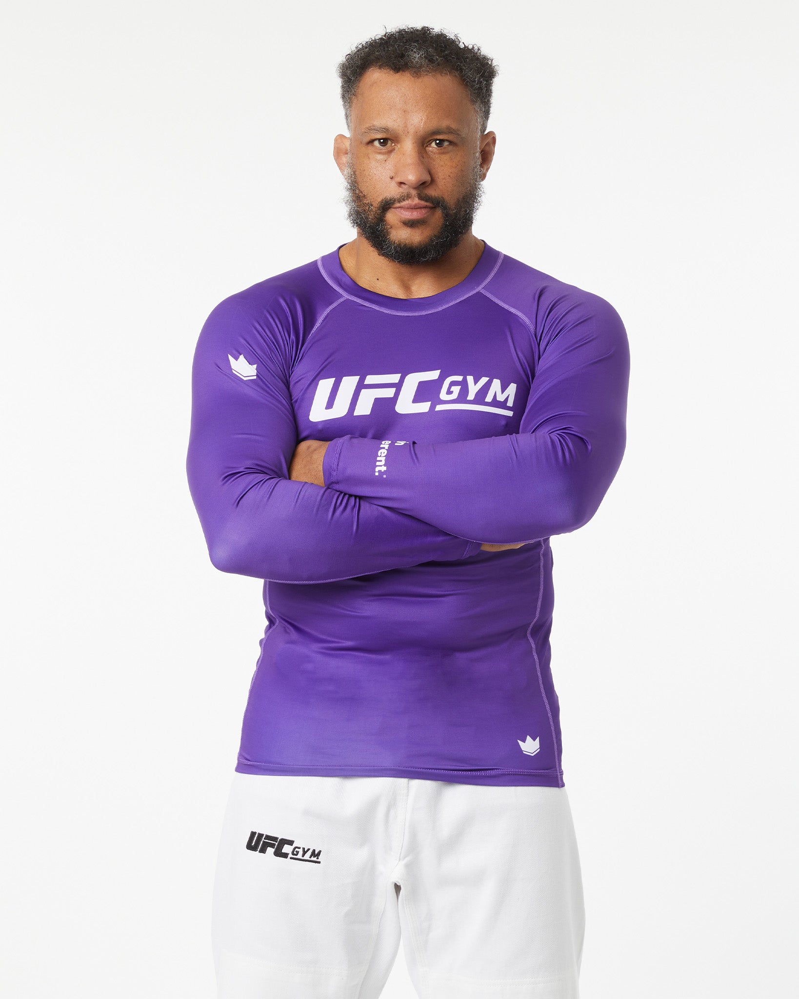 Person wearing a purple UFC Gym long-sleeve shirt and white pants on a white background