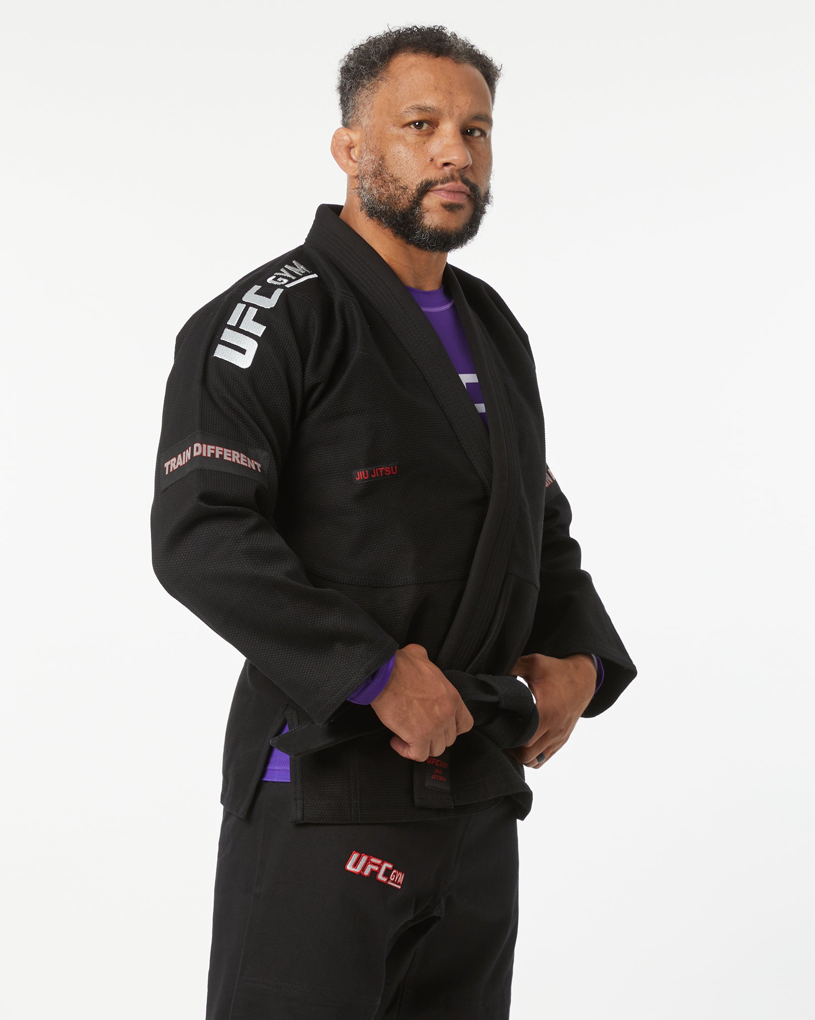 Person wearing a black UFC branded gi on a white background facing right looking forward