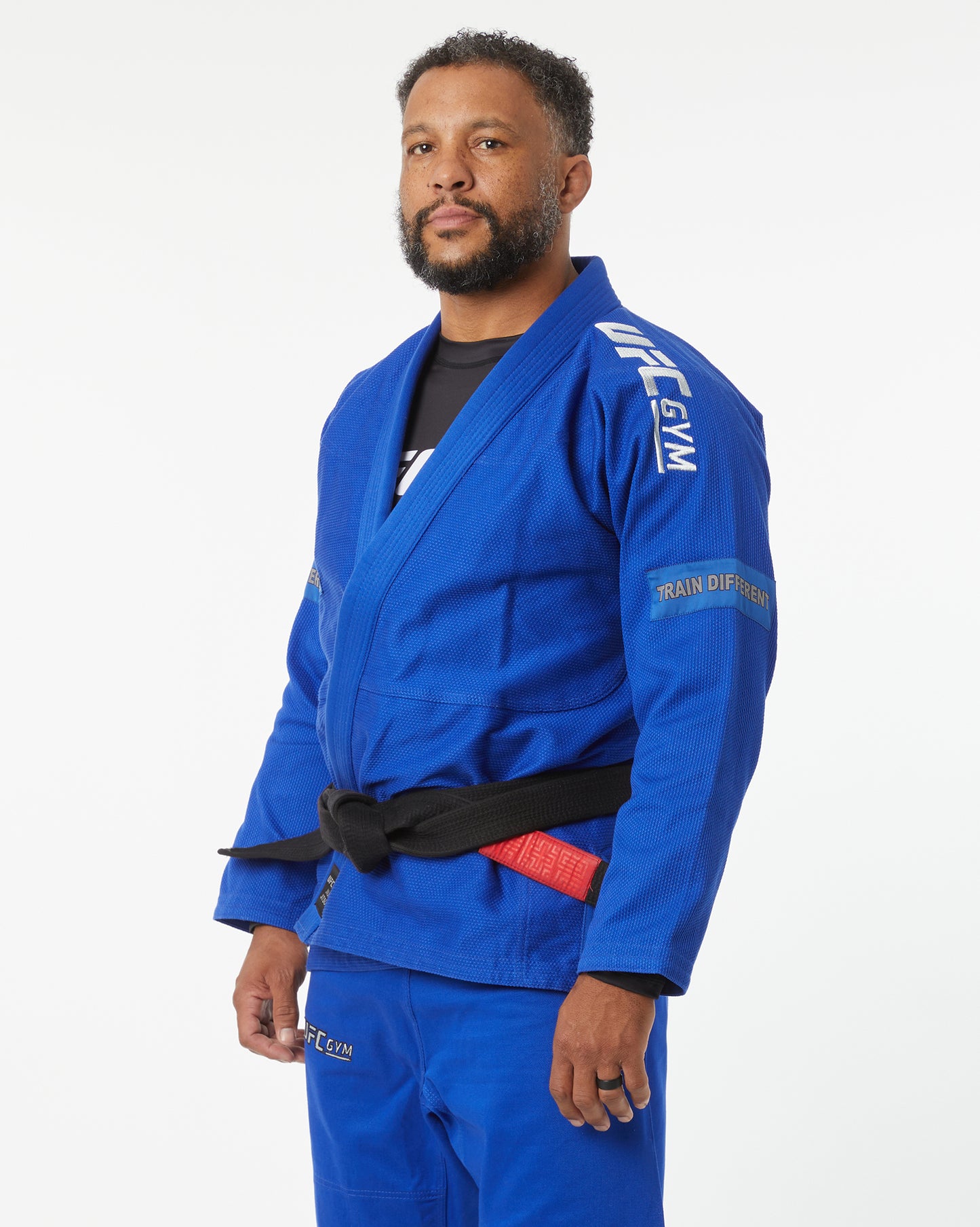 Man wearing a blue UFC Gym uniform on a white background left-facing looking forward