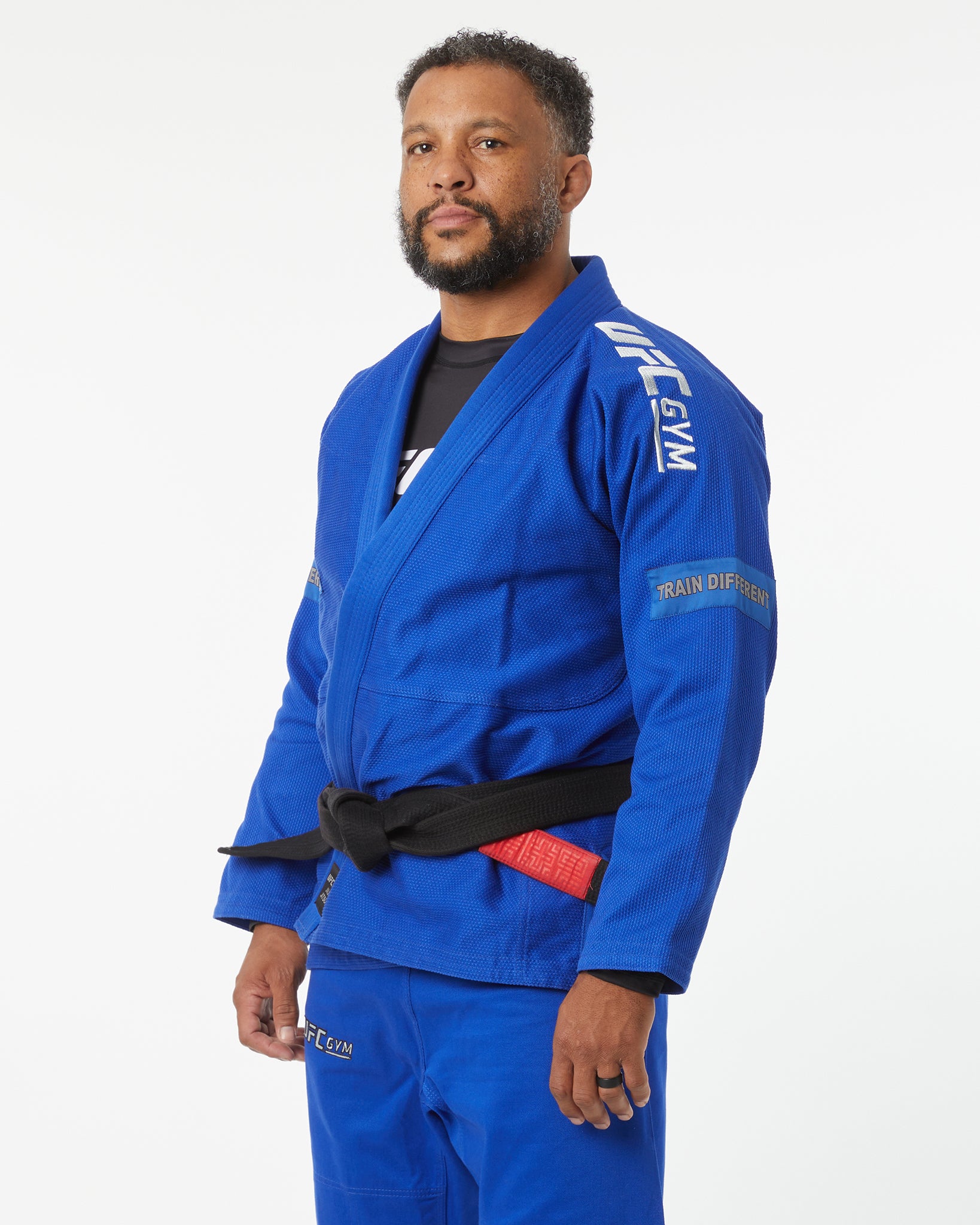Man wearing a blue UFC Gym uniform on a white background left-facing looking forward