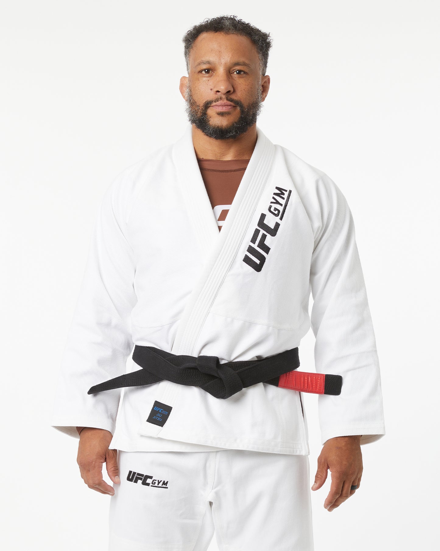 Man wearing a white UFC Gym kimono with a black belt on a white background facing forward