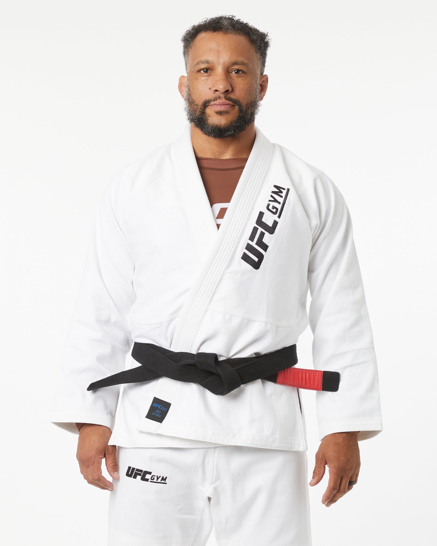 Man wearing a white UFC Gym kimono with a black belt on a white background facing forward