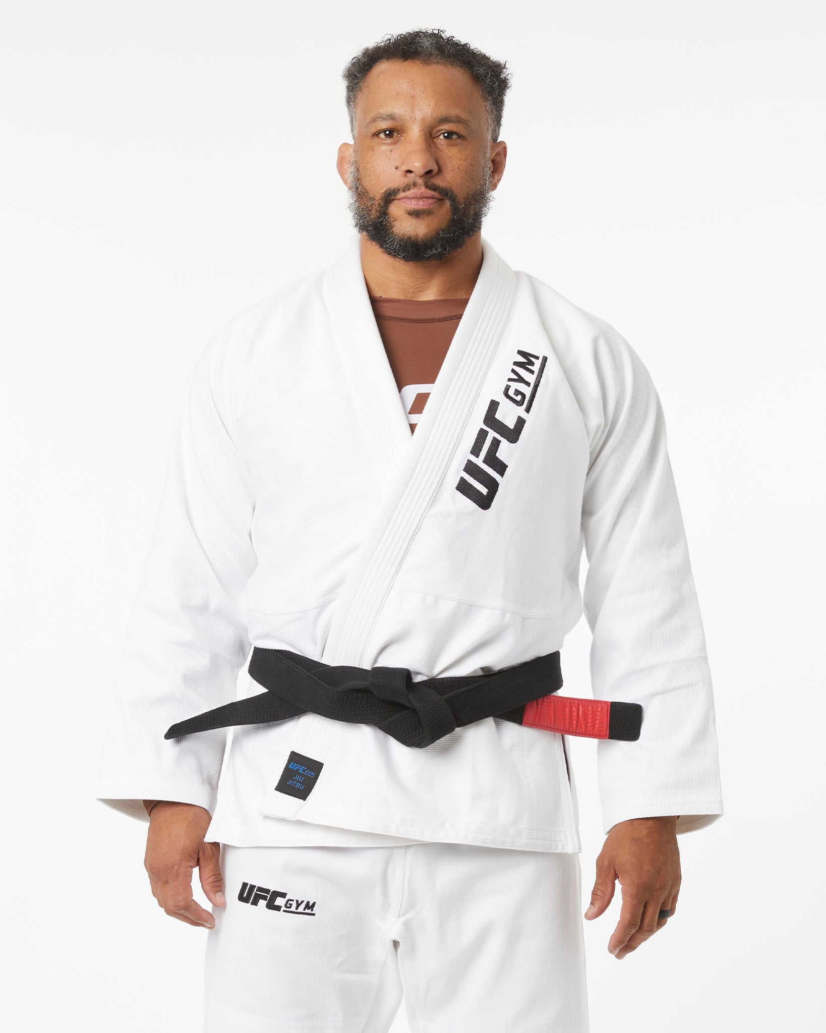 Man wearing a white UFC Gym kimono with a black belt on a white background facing forward