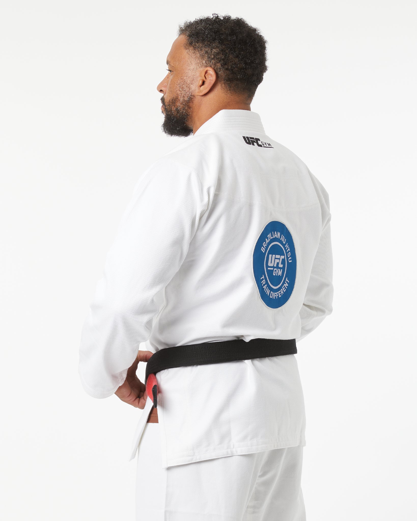 Person wearing a white UFC uniform with a blue patch on the back, facing slightly back to the left